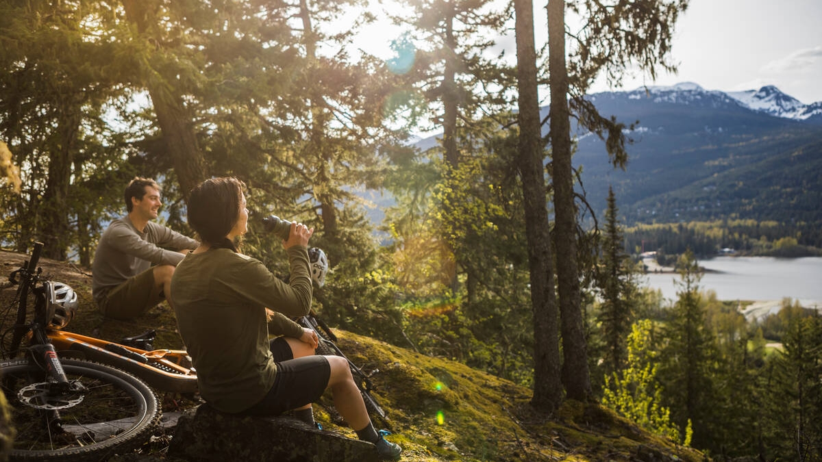 Two mountain bikers take a break on a trail in Whistler.