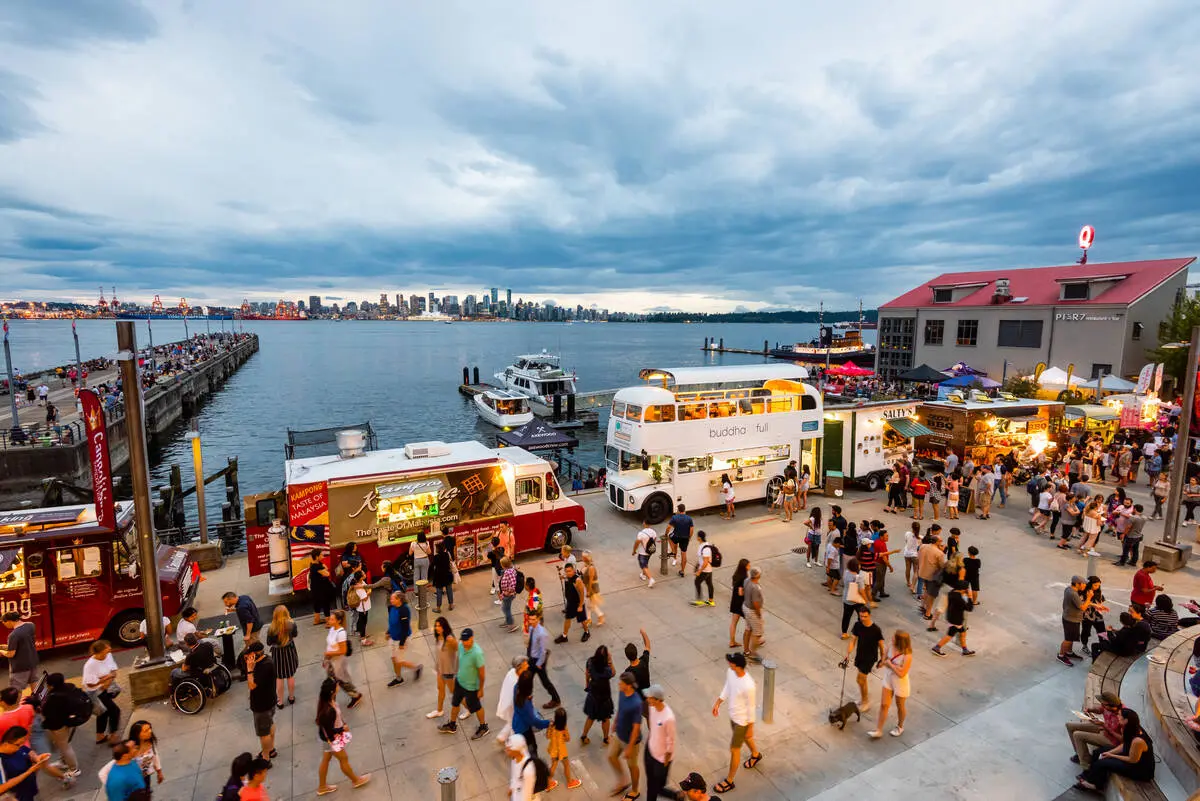People stroll past food trucks at the Shipyards Night Market