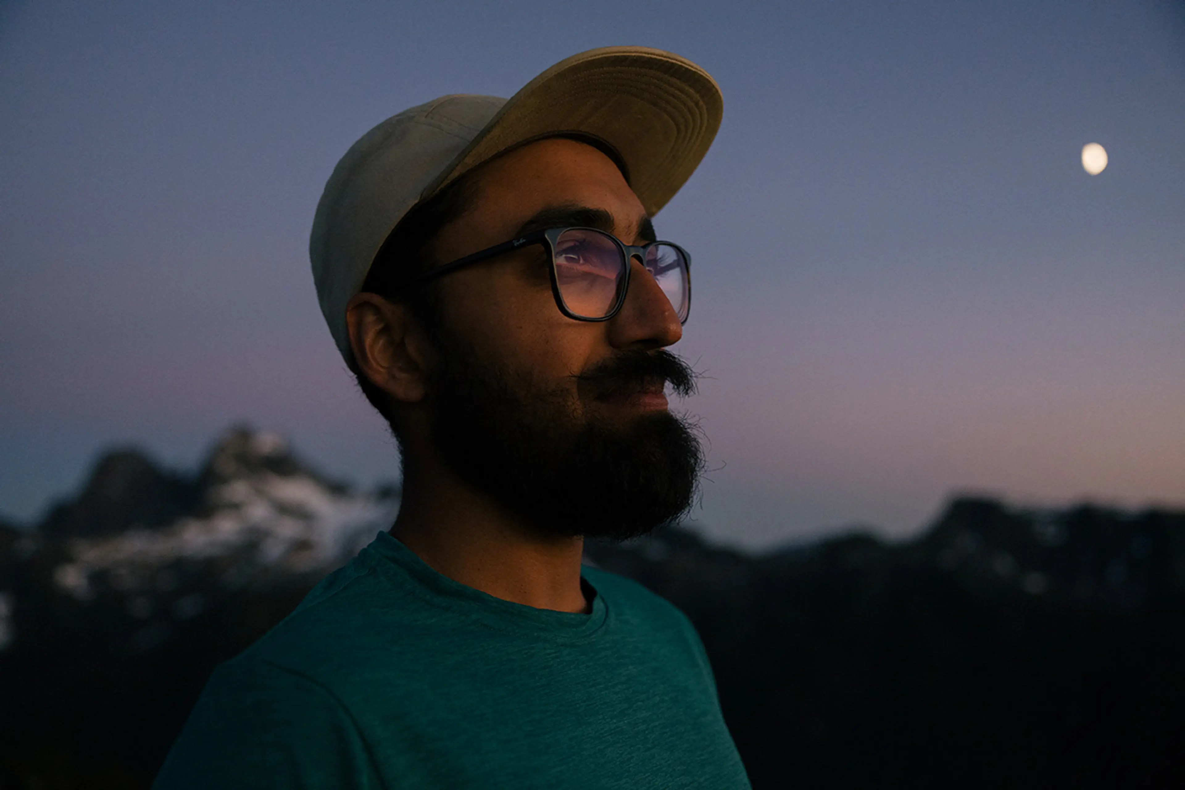 Trail runner JoJo Das stands atop a mountain at dusk. 