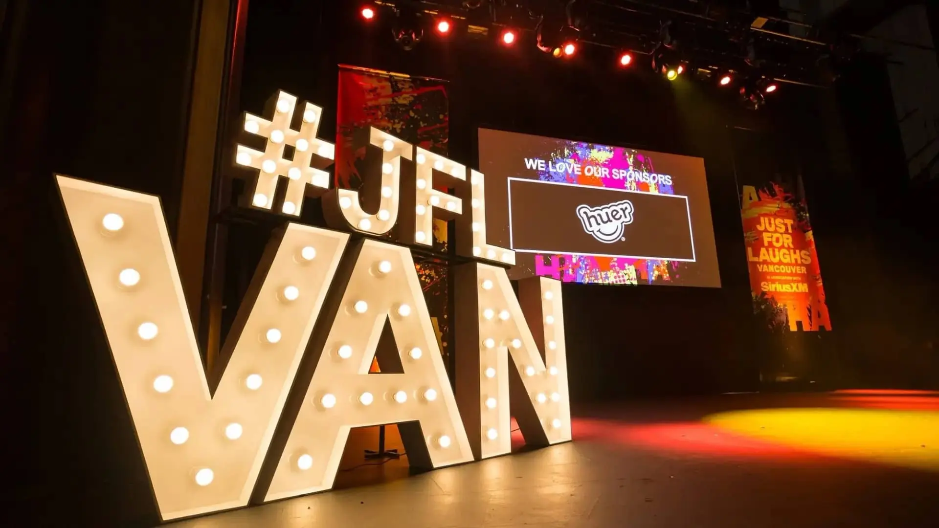 A stage with a big signage with lights for just for laughs