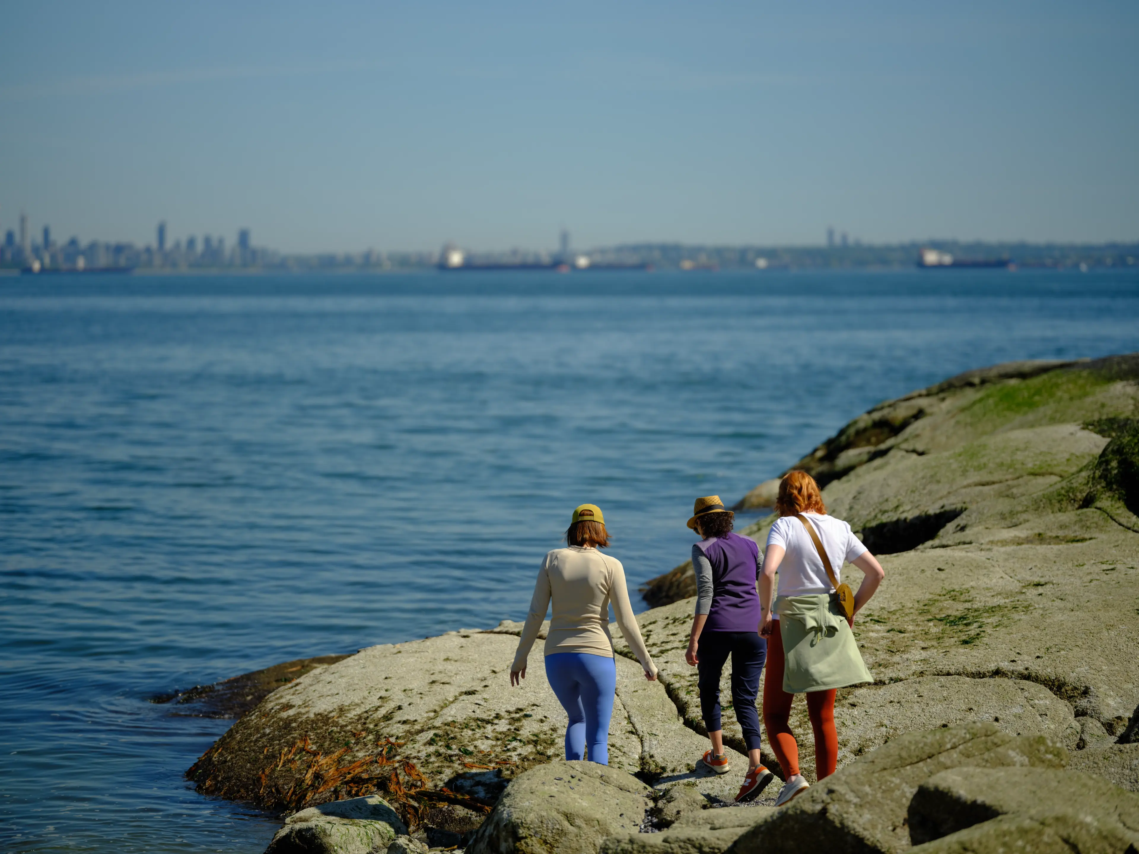 Three women hiking on rocks at the oceanfront in West Vancouver.