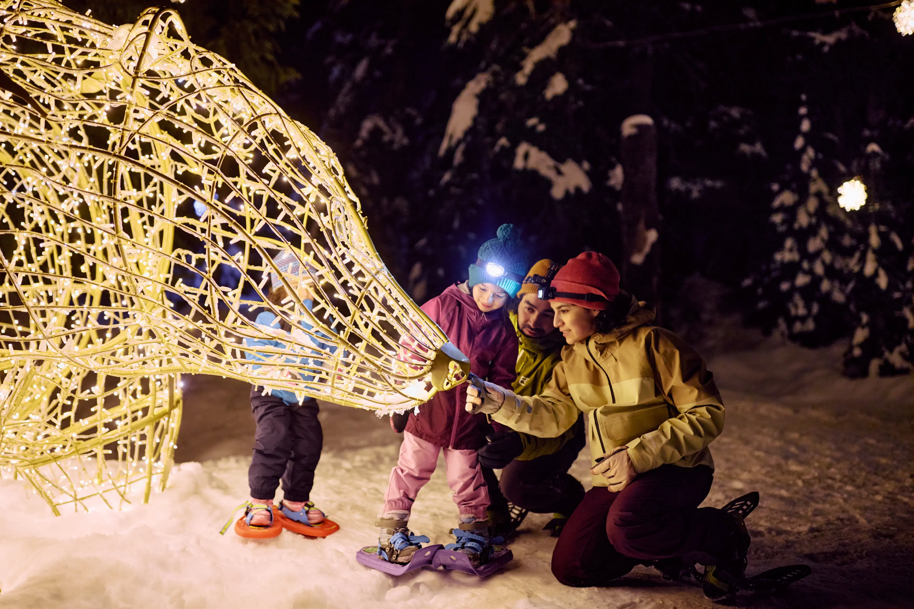 A mom and a child snowhoeing the Light walk during Grouse Mountain's Peak of Christmas.