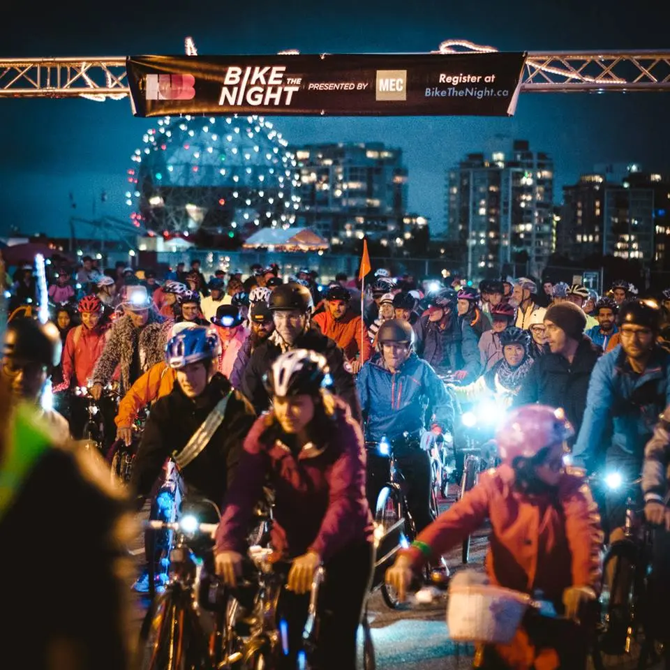 A group of cyclists rides in front of Science World at the Bike the Night Event in Vancouver, BC