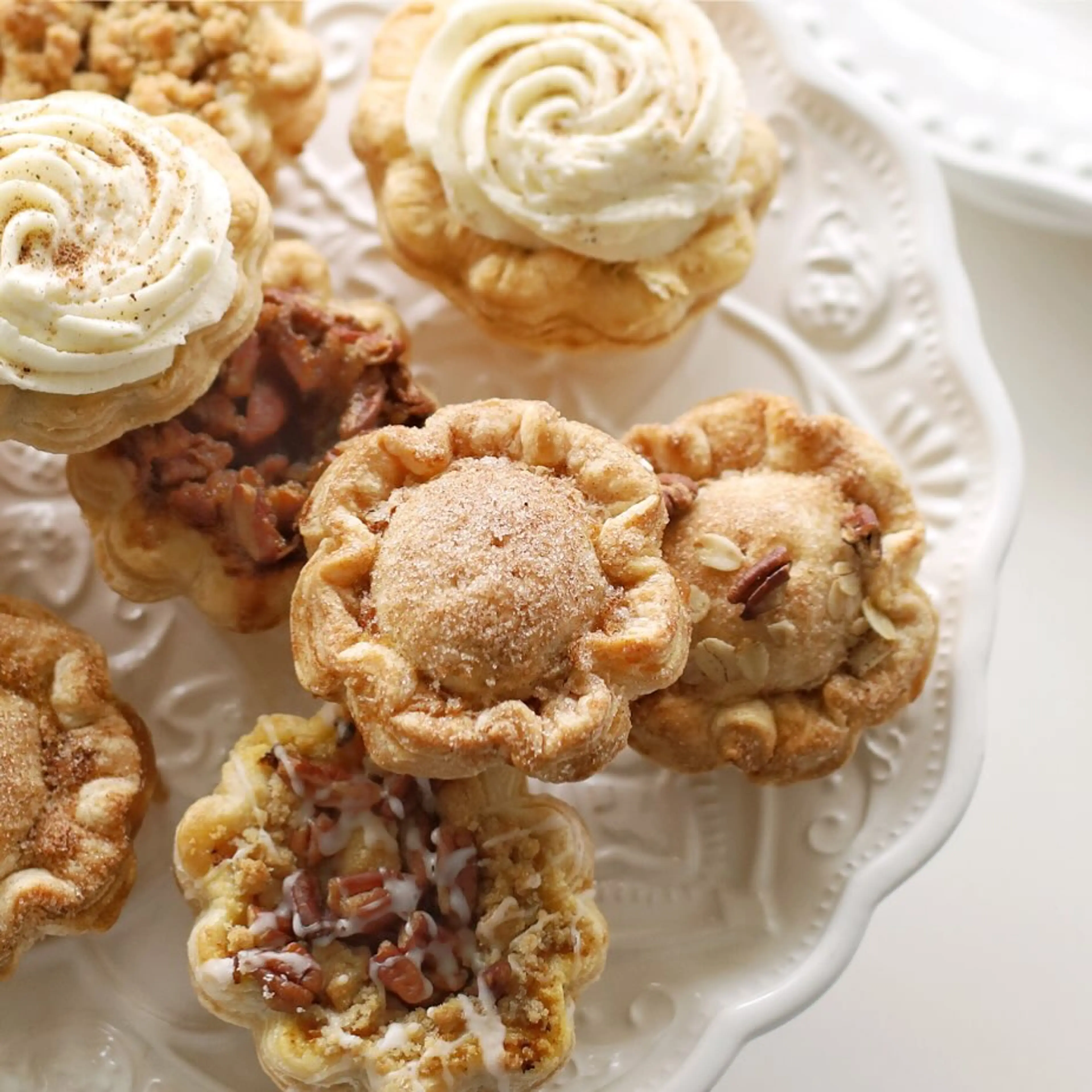 A group of mini holiday pies from The Pie Hole arranged on a white plate. 