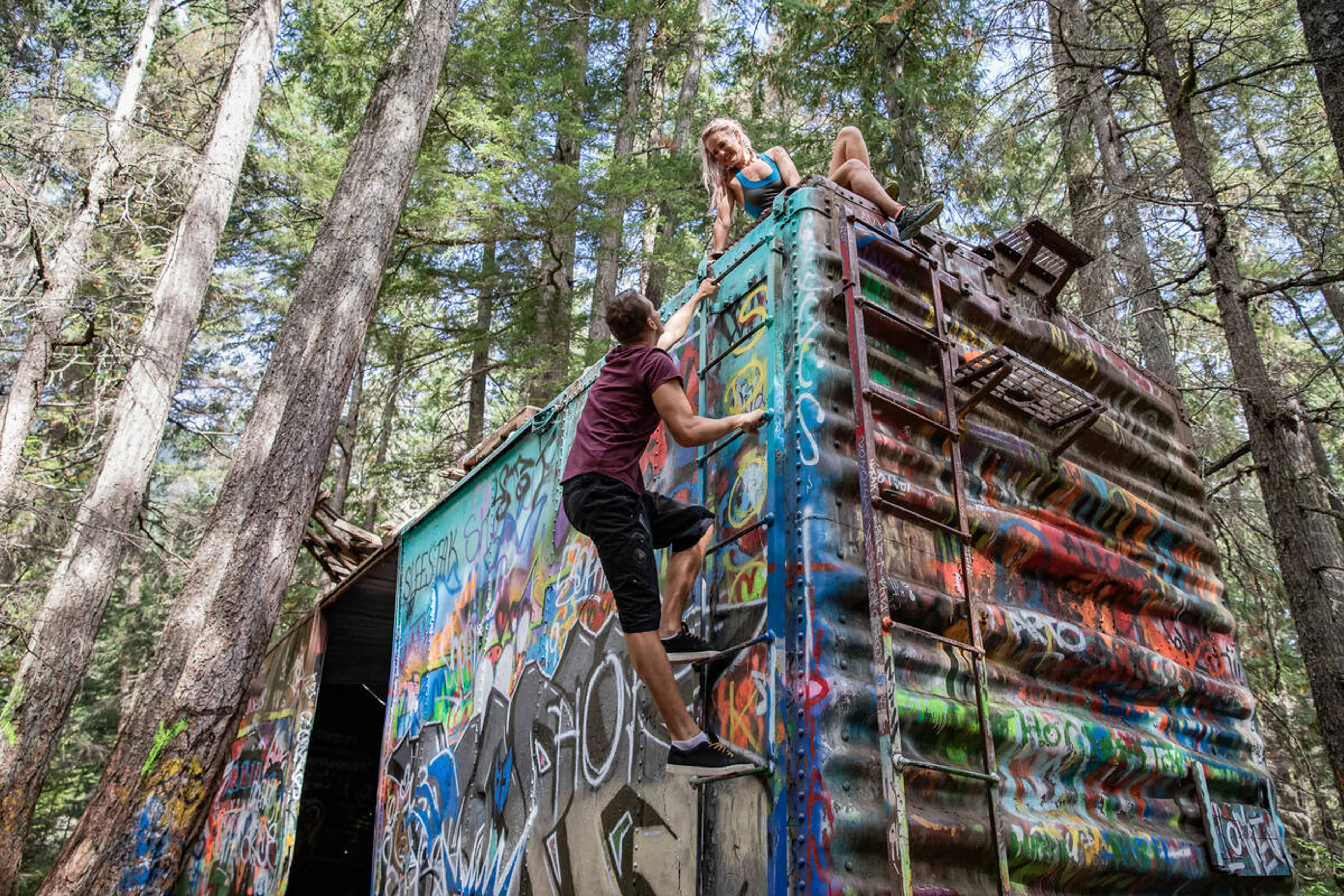 Two people explore an abandoned train car in Whistler
