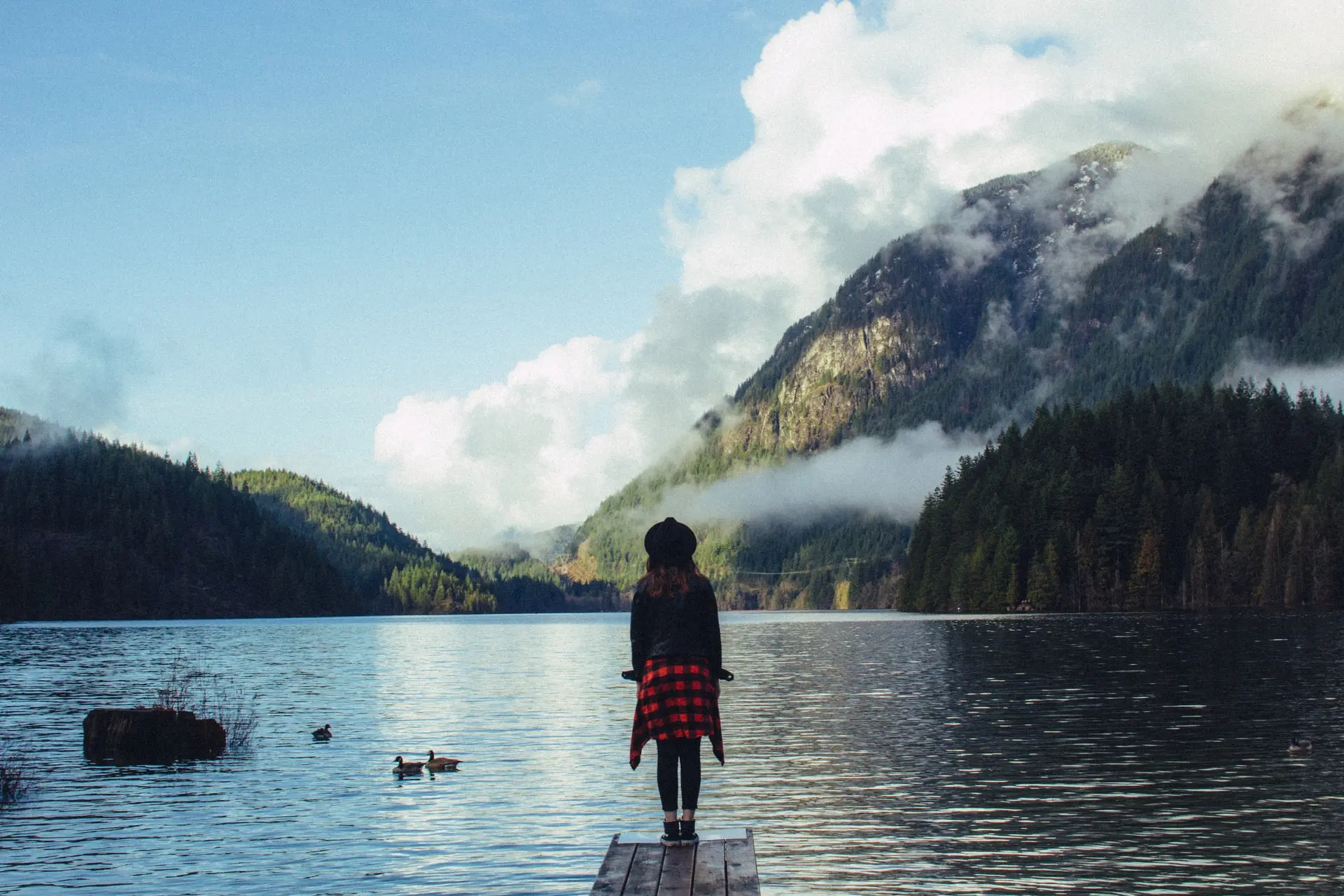 A woman stands on the shore of Buntzen Lake near Vancouver