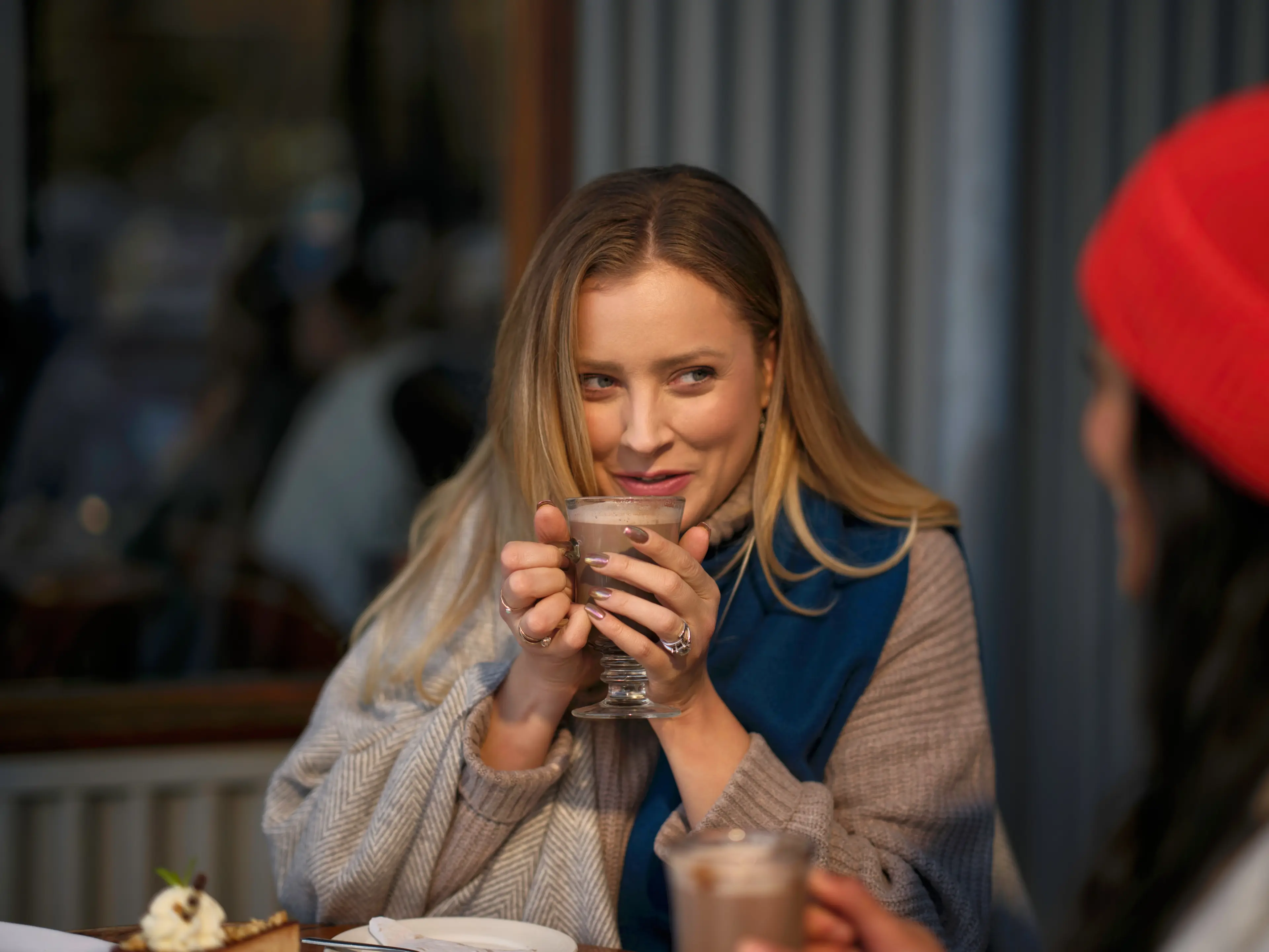 A women holding a steaming hot chocolate mug bundled up in warm clothes.