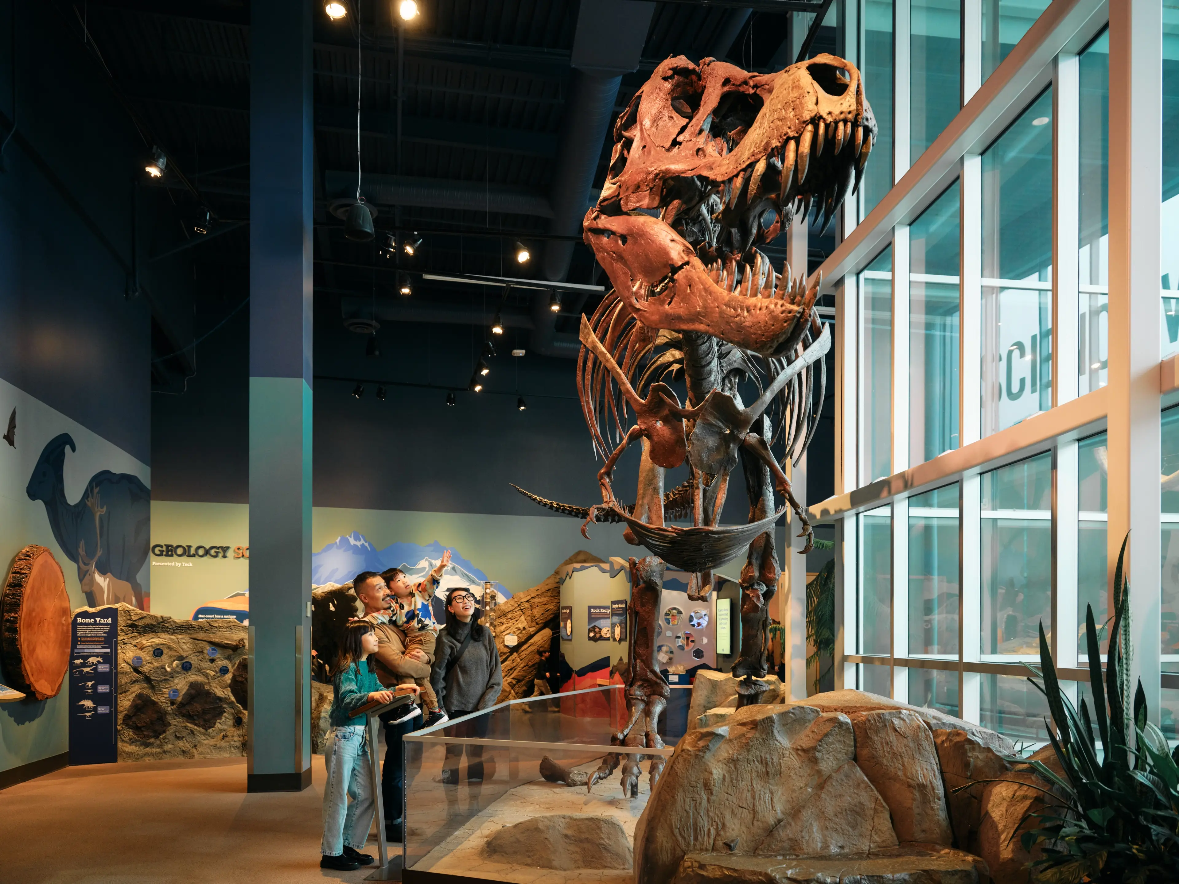 A family with two kids standing in front of a tyrannosaurus rex skeleton at Science World in Vancouver.