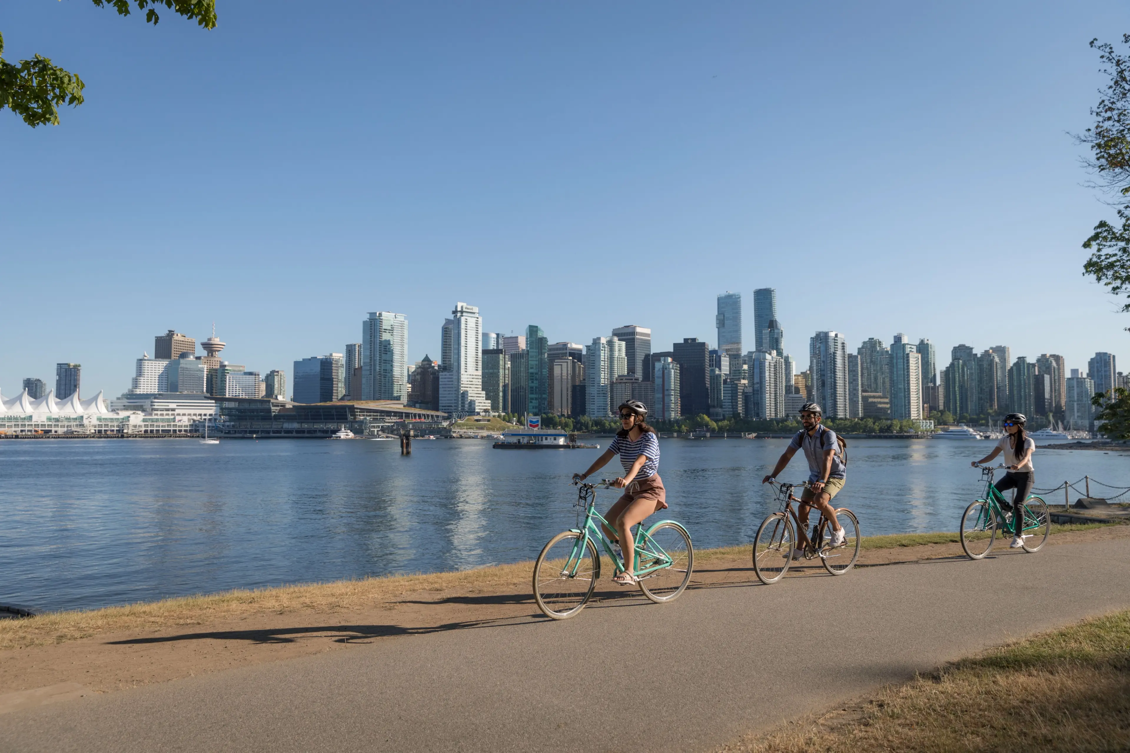 Three people biking in Vancouver along the water.