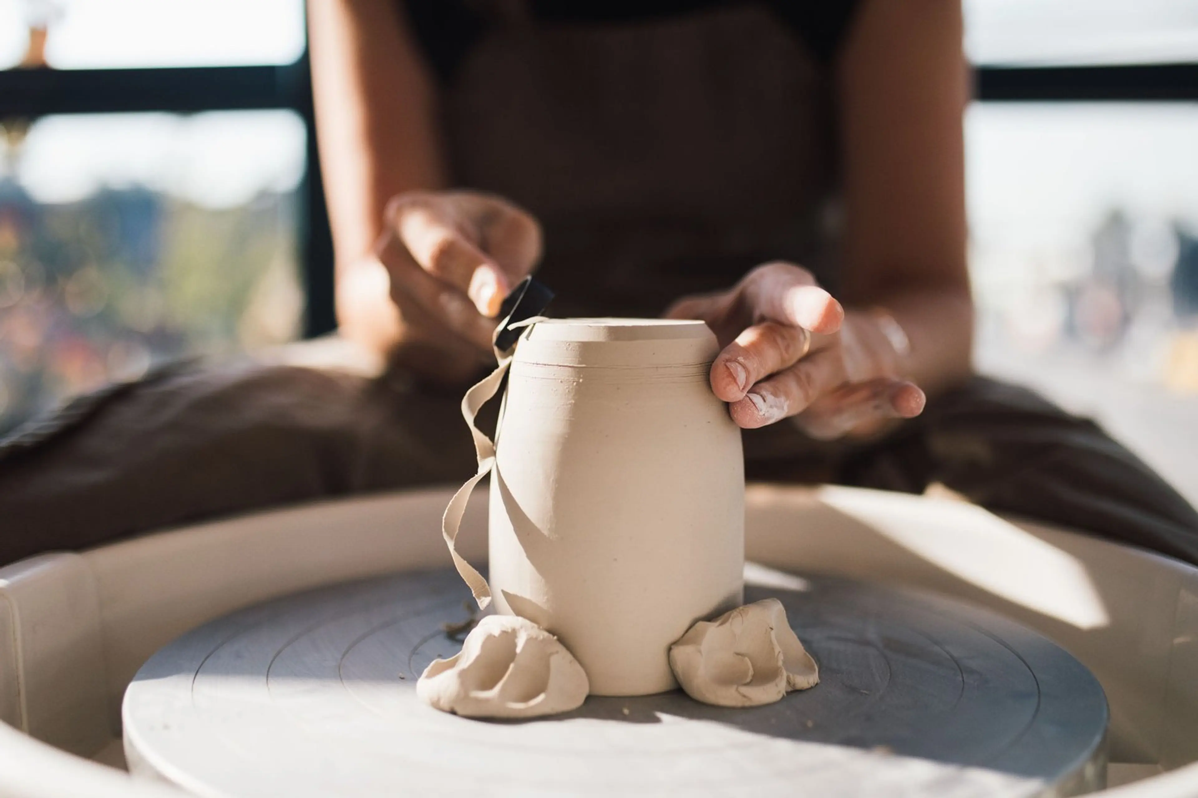 Close-up of a pair of hands manipulating clay on a pottery wheel at Claymates in Vancouver.