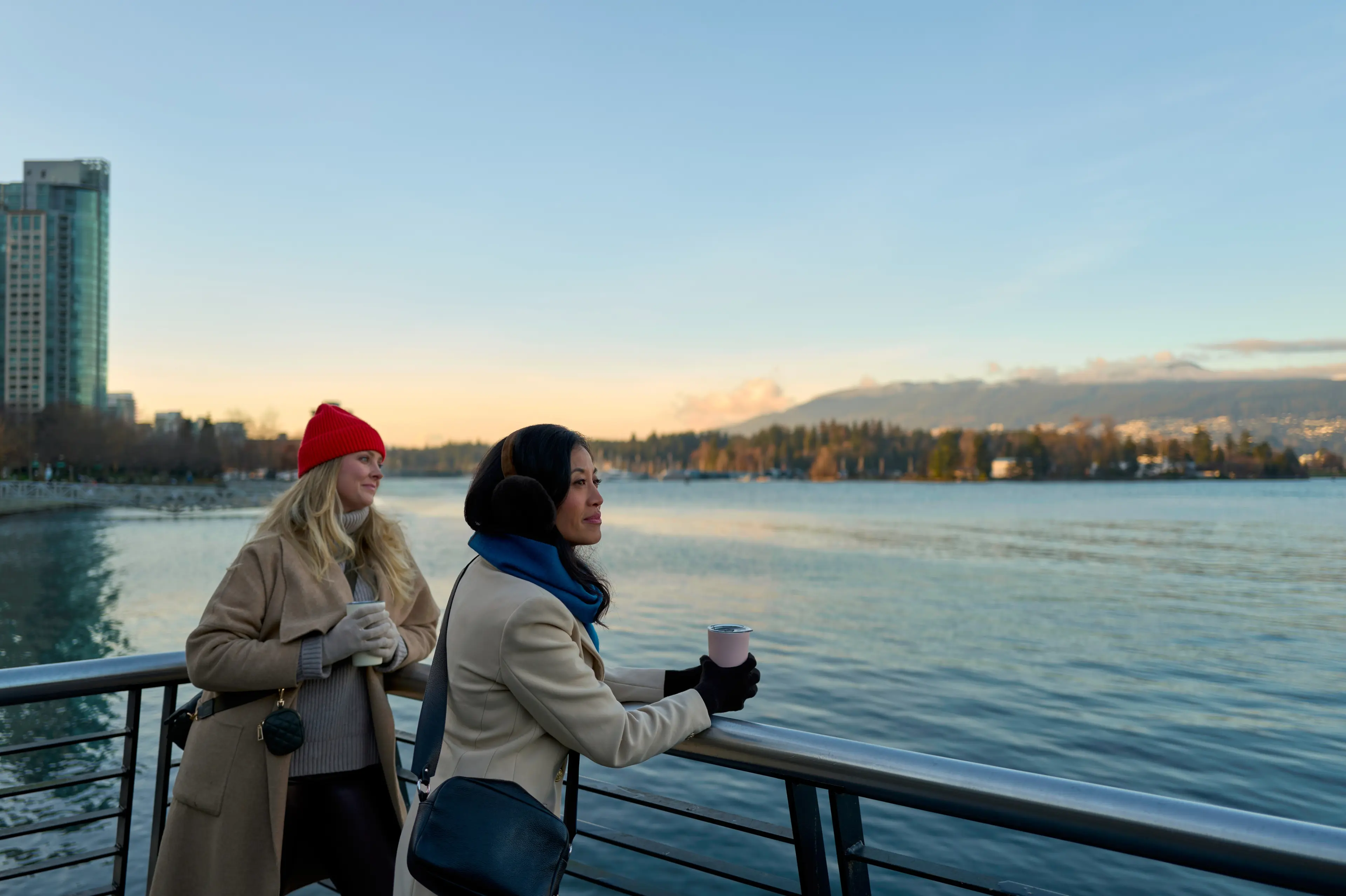 Two women drinking to-go cups of coffee in Coal Harbour