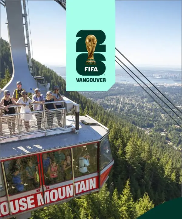 People wearing helmets on top and inside a Grouse Mountain cable car with a forest and city view in the background.