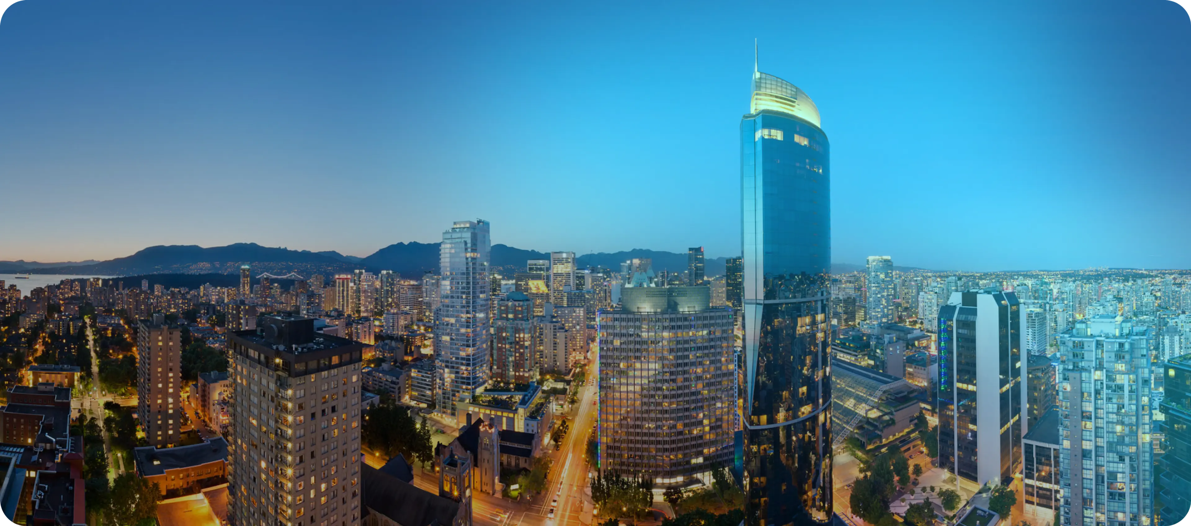 Vancouver's shining glass skyscrapers lit up at night with streets glowing from traffic