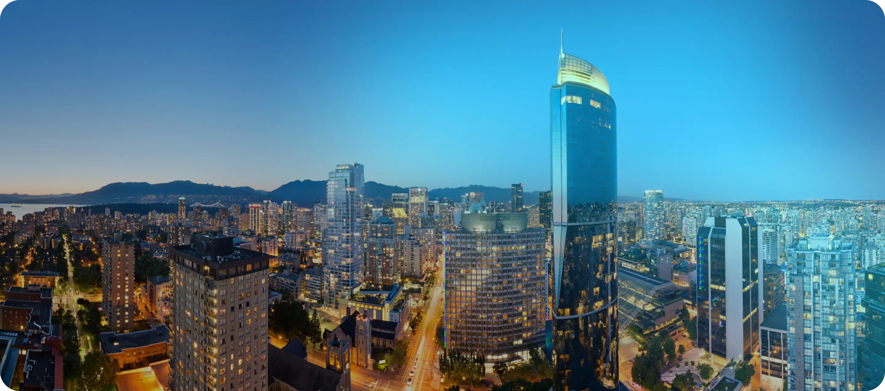 Vancouver's shining glass skyscrapers lit up at night with streets glowing from traffic