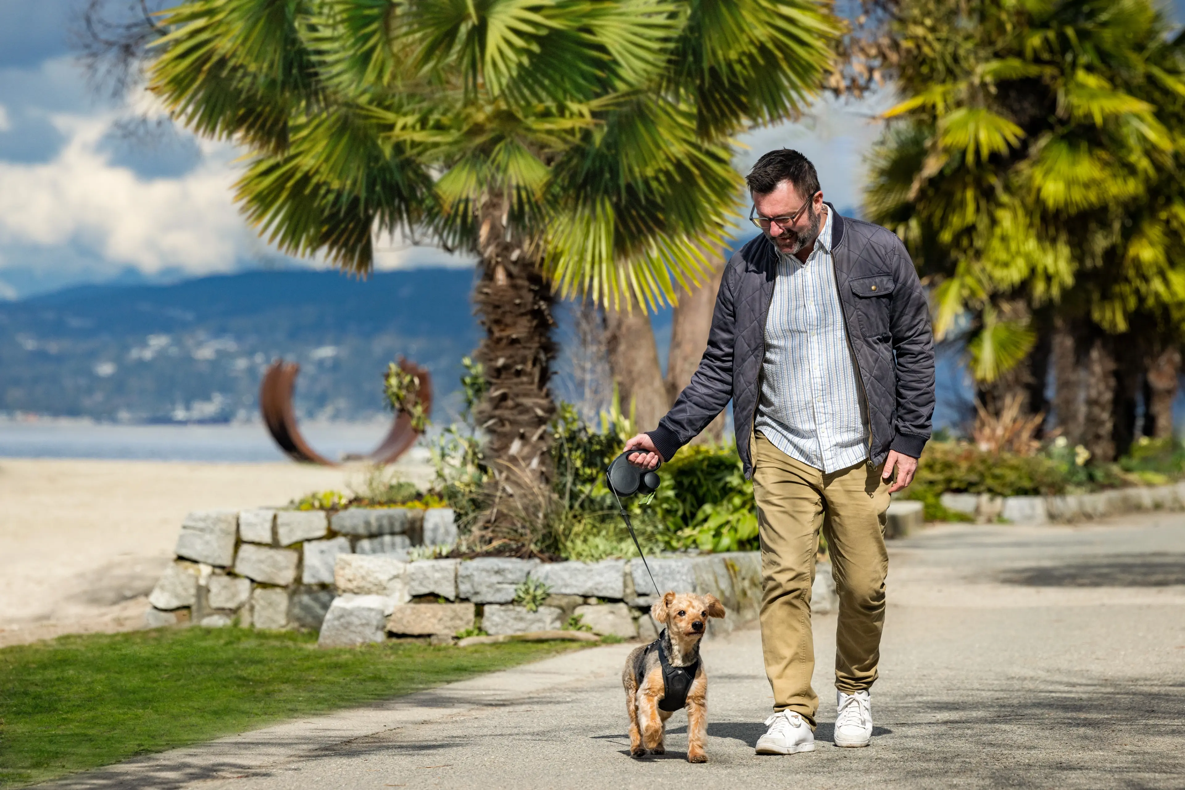 A man walks on a dog on the False Creek Seawall near Sunset Beach