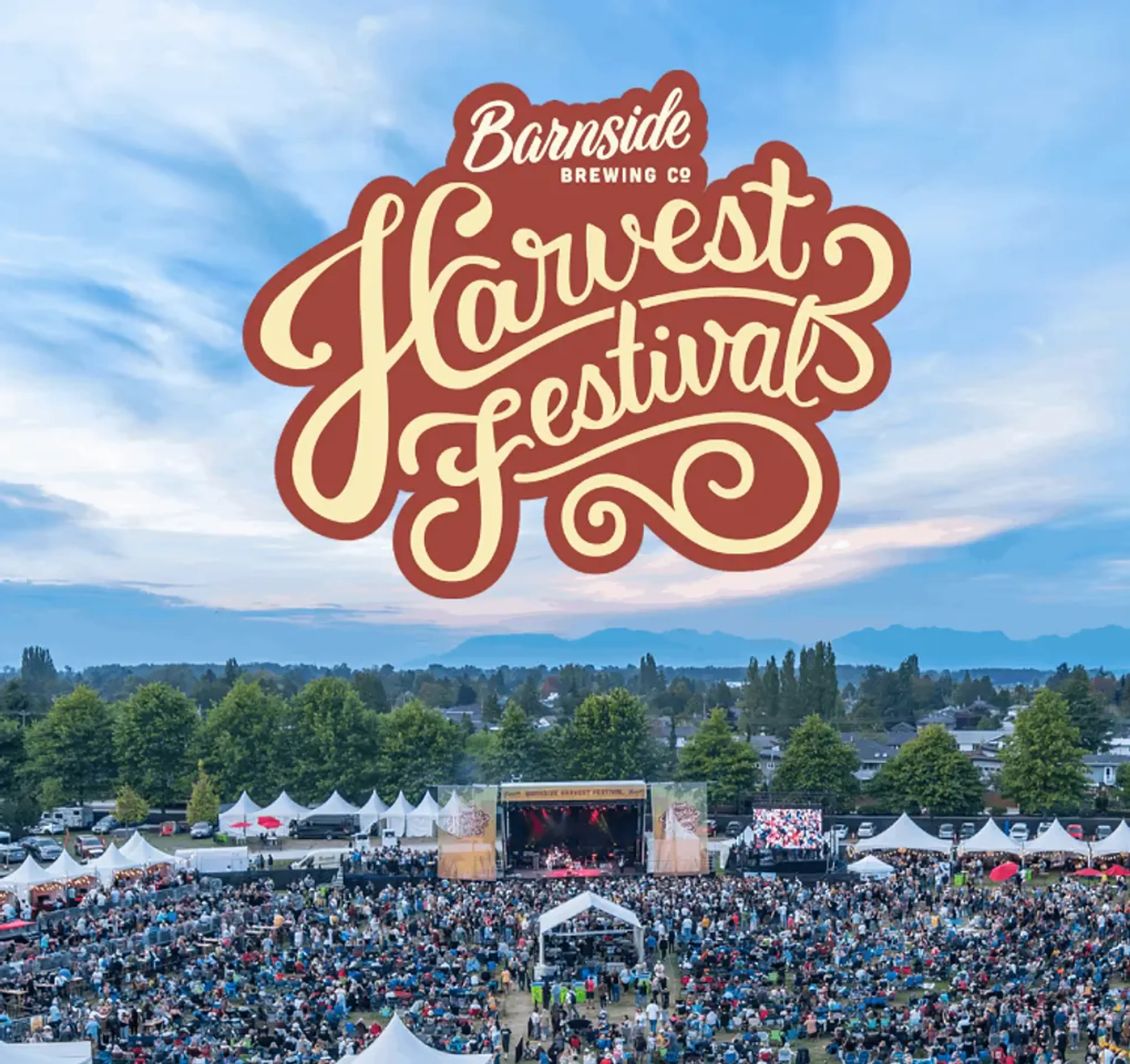 Large outdoor crowd at a festival with tents and a stage under a blue sky with text Barnside Brewing Co Harvest Festival
