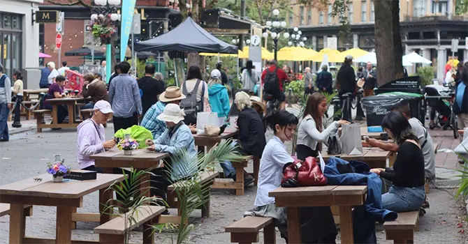 People sit at tables in the Water Street pedestrian zone in Vancouver