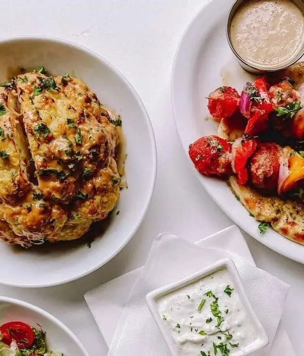 Greek food with Roasted Whole Cauliflower, Souvlaki Skewers, Tzatziki Sauce, and Salad and Vegetables