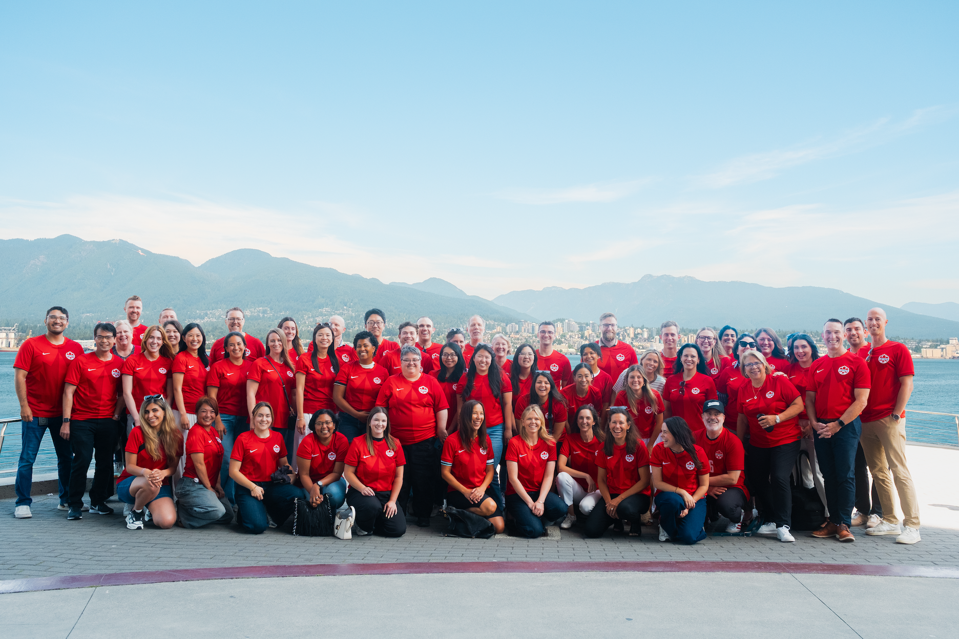 The Destination Vancouver Team posing for a team photo and wearing Canadian football jerseys