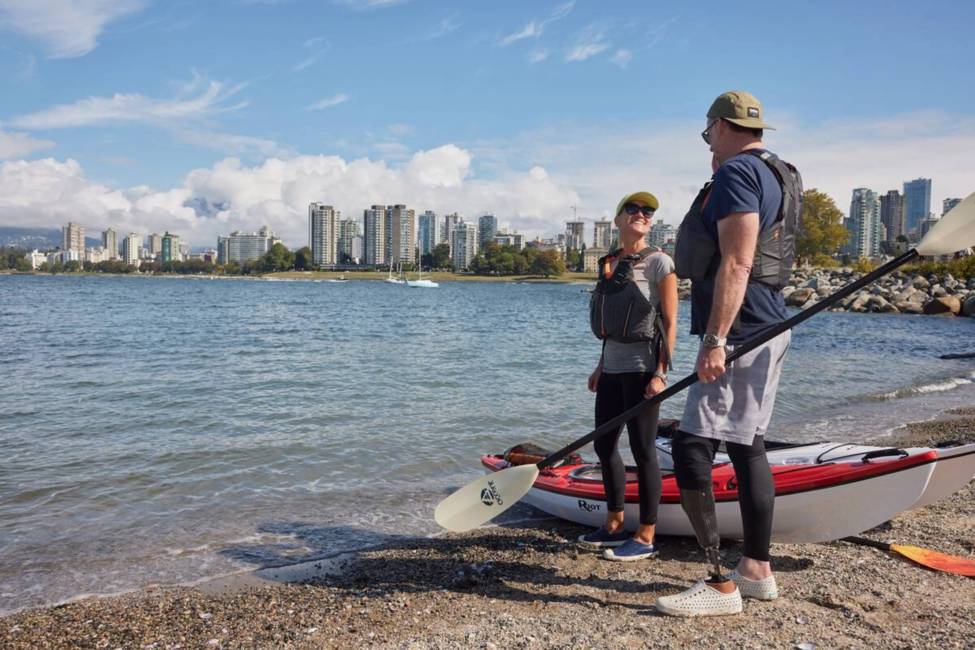 Two people get ready to go kayaking on a beach in Vancouver. 