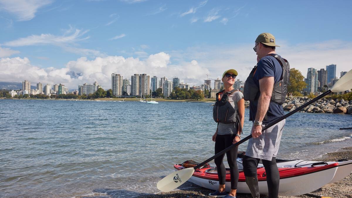 Two people get ready to go kayaking on a beach in Vancouver.
