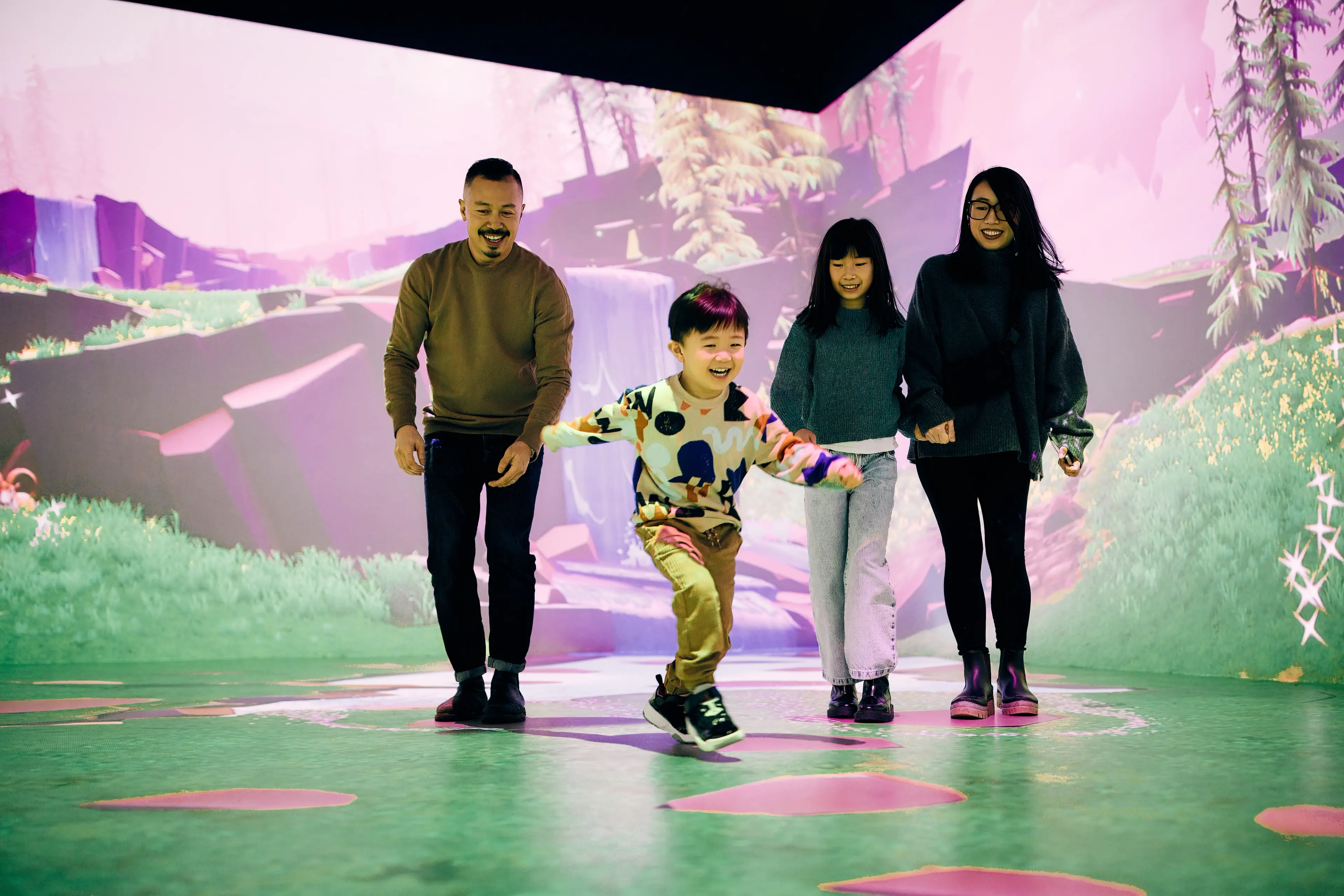 Two kids jumping with their parents in an interactive room at Science World in Vancouver.