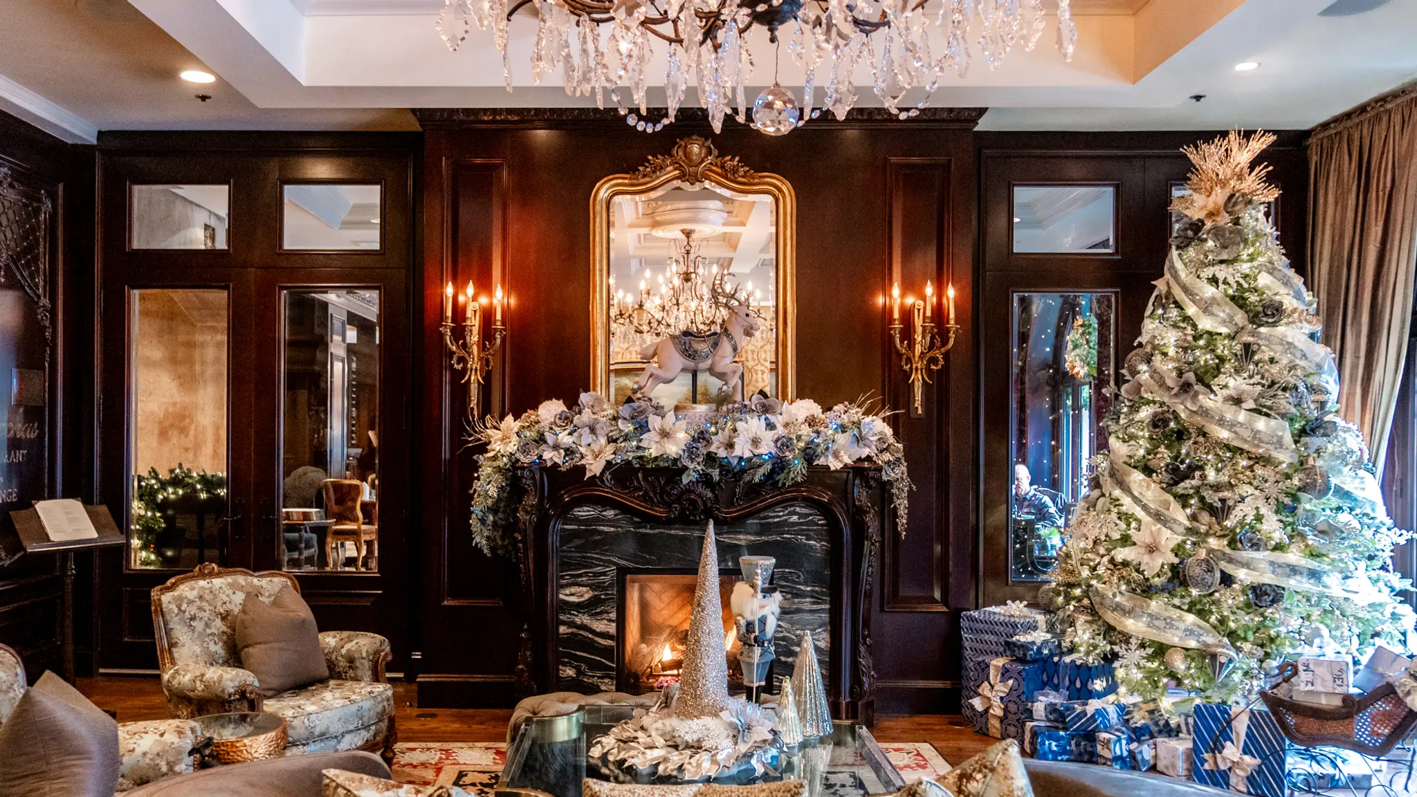 A Christmas tree to the right of a decorated fireplace at the Wedgewood Hotel's lobby