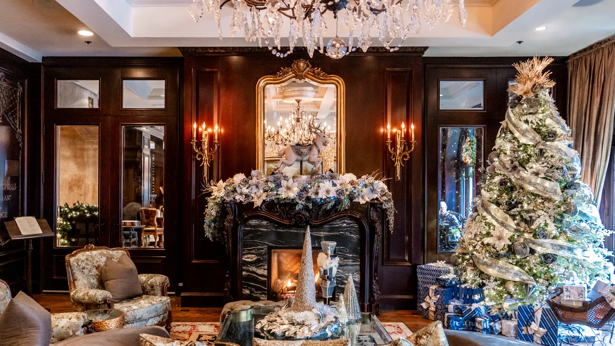A Christmas tree to the right of a decorated fireplace at the Wedgewood Hotel's lobby