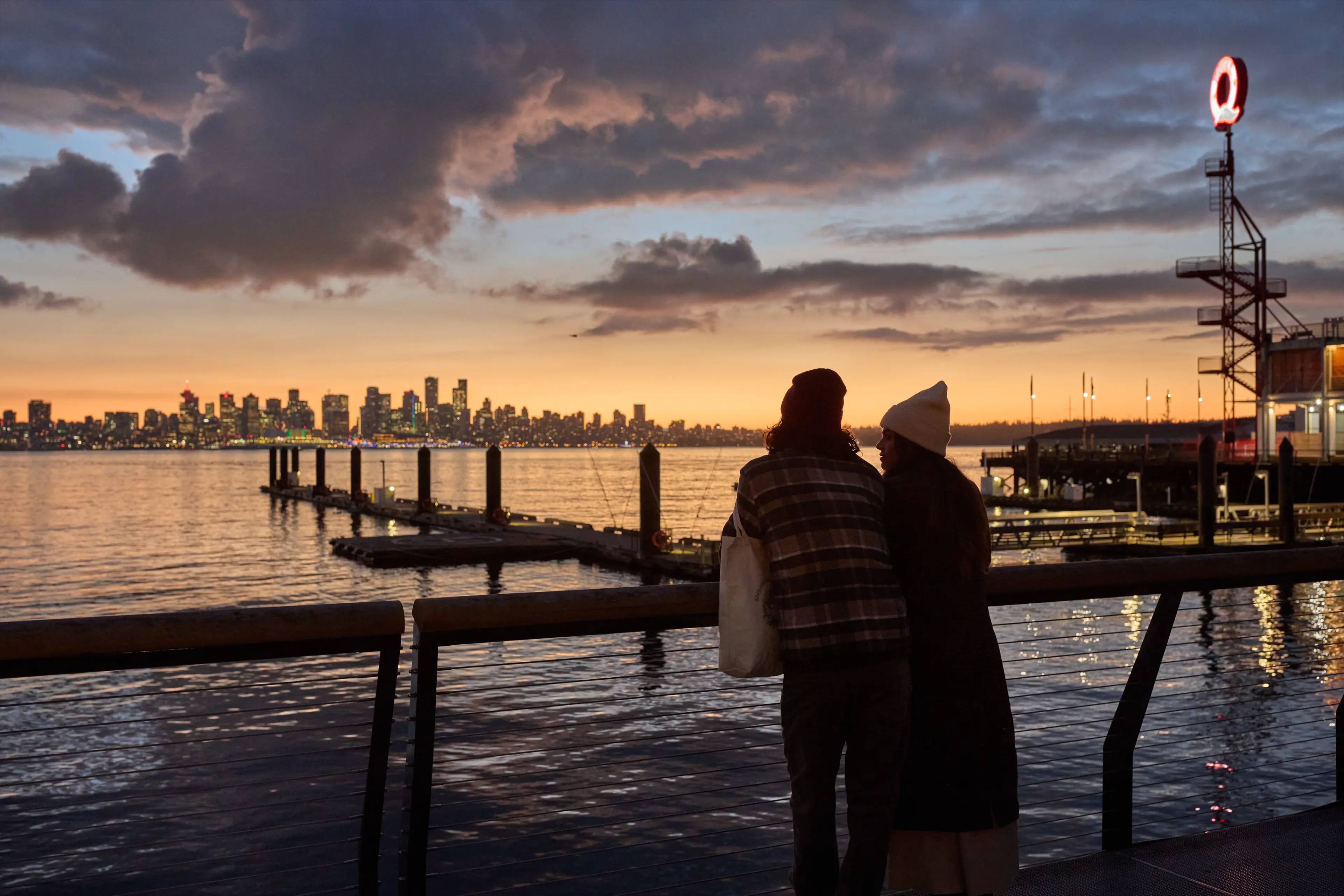 A couple looking out to the downtown skyline at the Shipyards in North Vancouver.