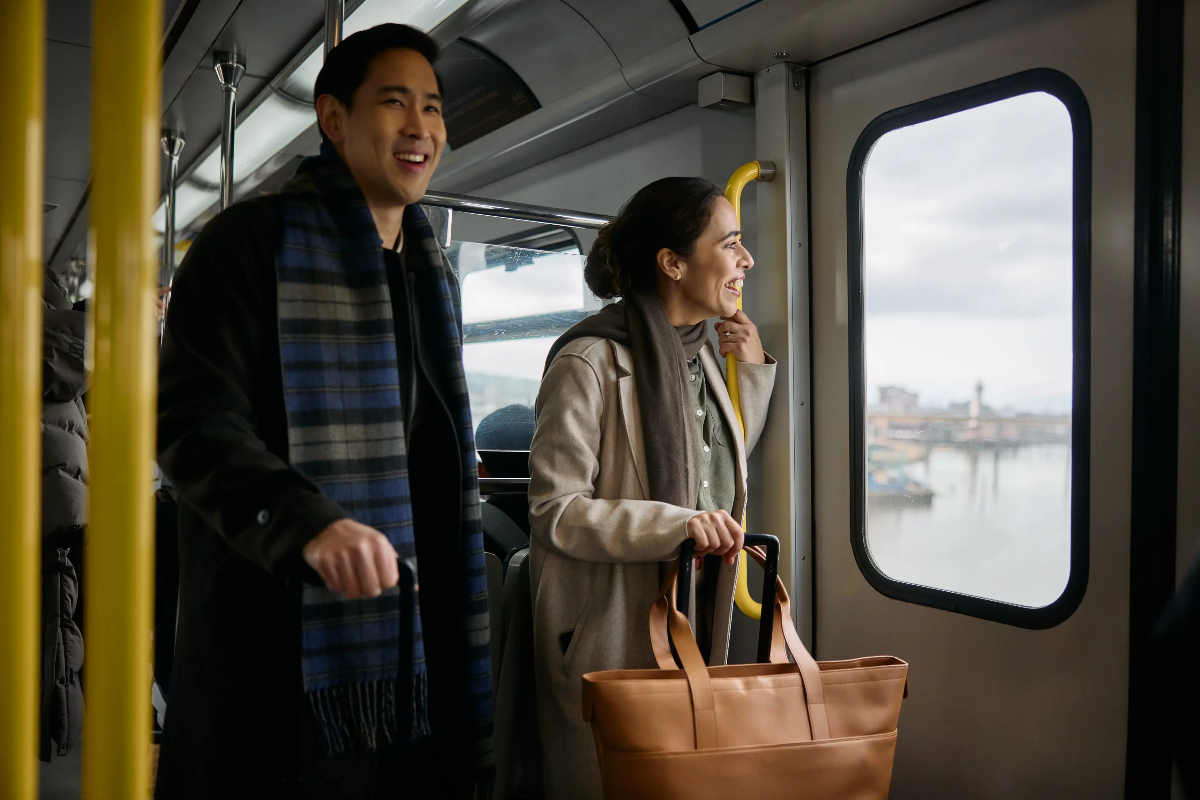 Two people taking public transit in Vancouver and looking out of the SkyTrain.
