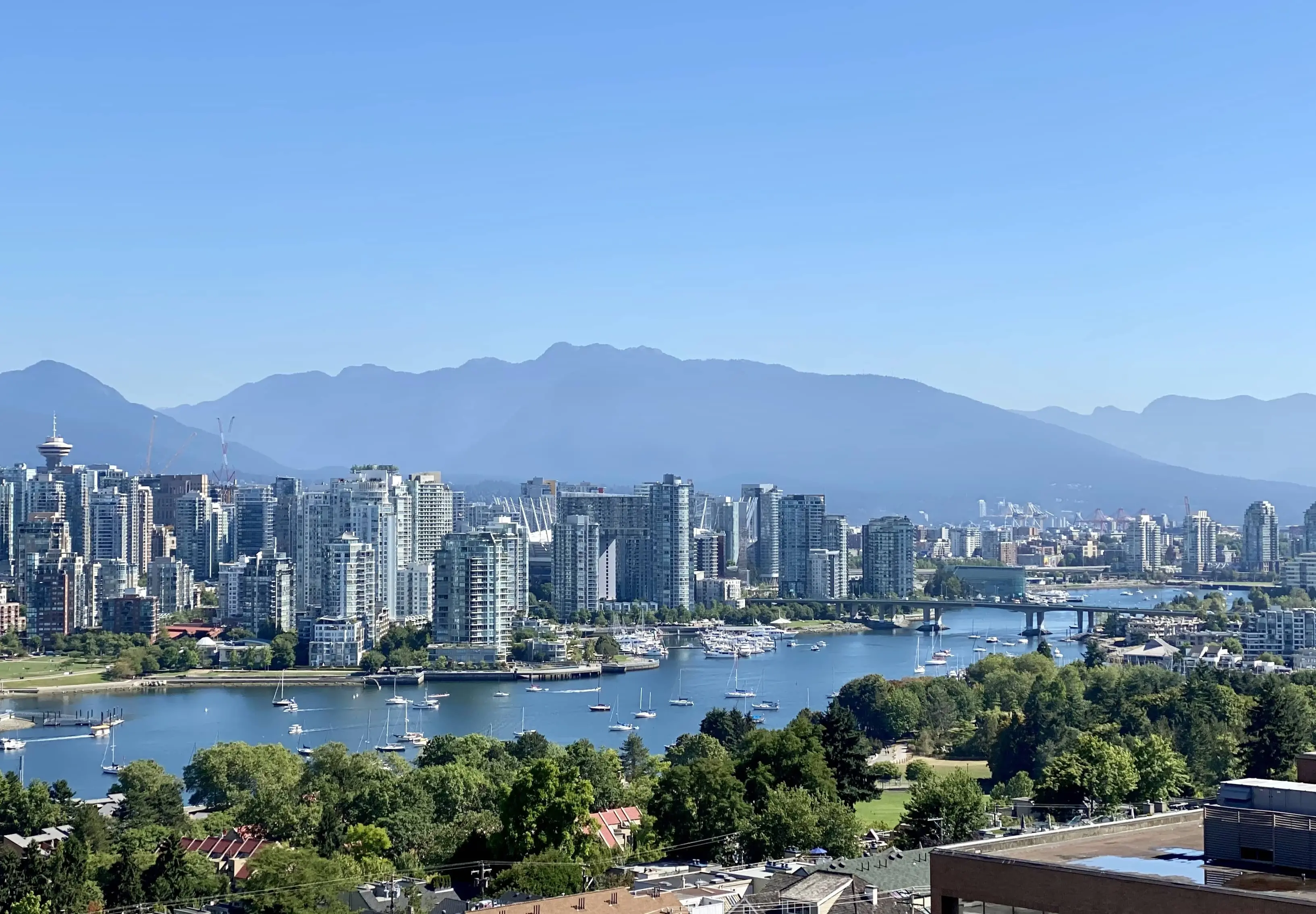 Landscape of Vancouver with the skyscrapers bordering the Fraser River, with mountains and blue sky above
