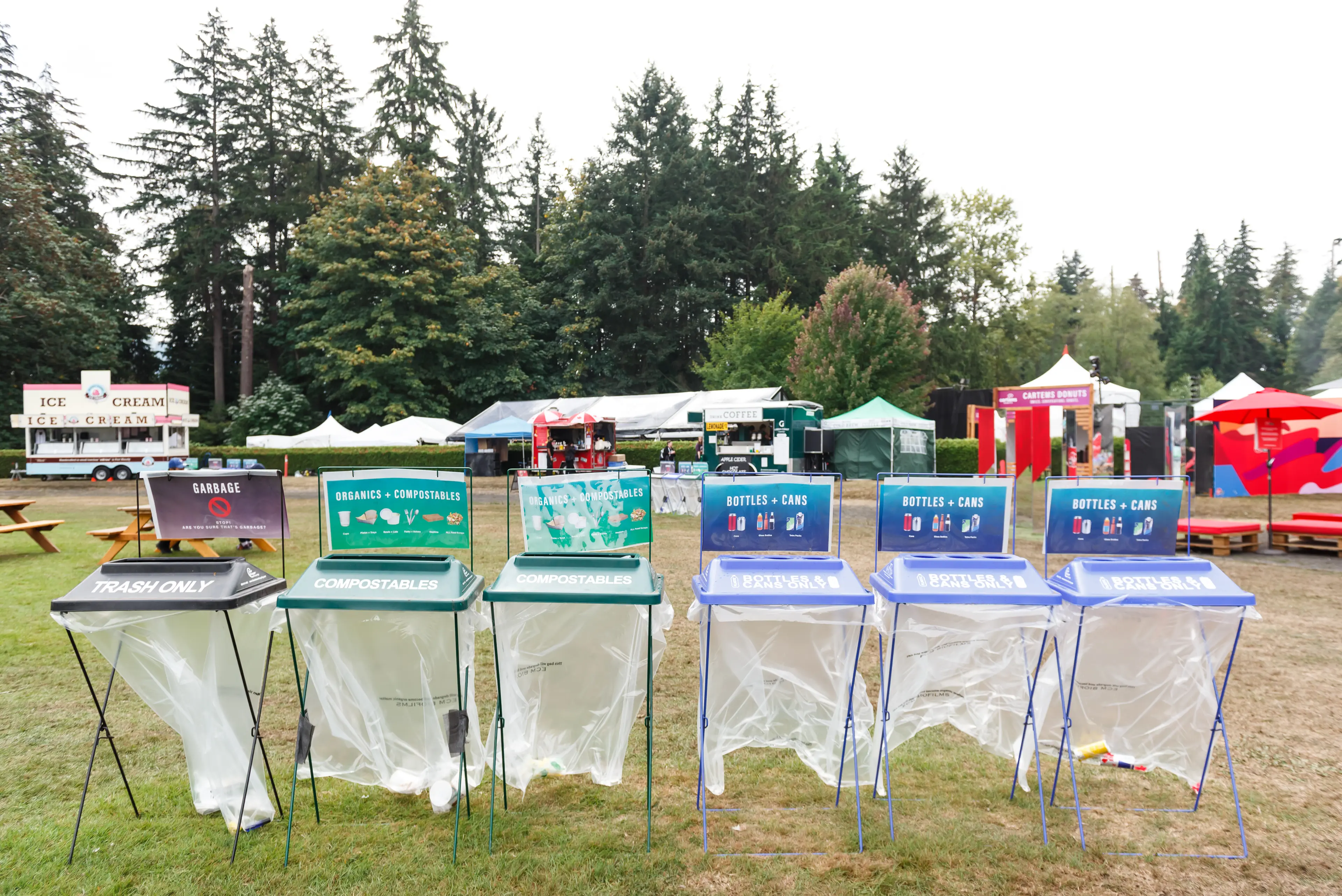 Recyling bins at the 2018 SKOOKUM Music Festival. Food trucks and Stanley Park trees in the background.