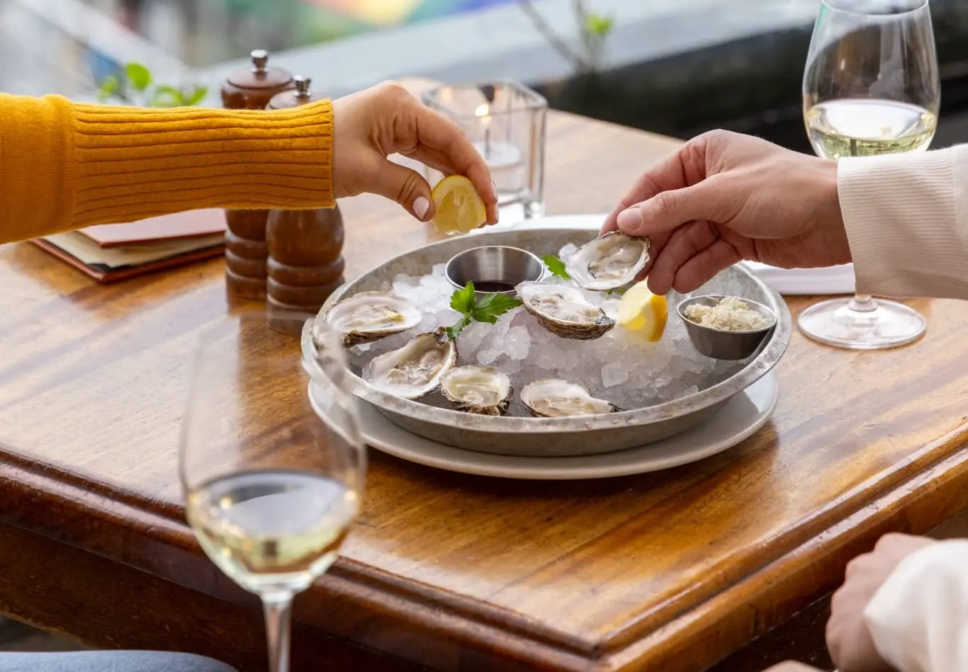 A Vancouver restaurant with people sharing white wine and fresh oysters on ice