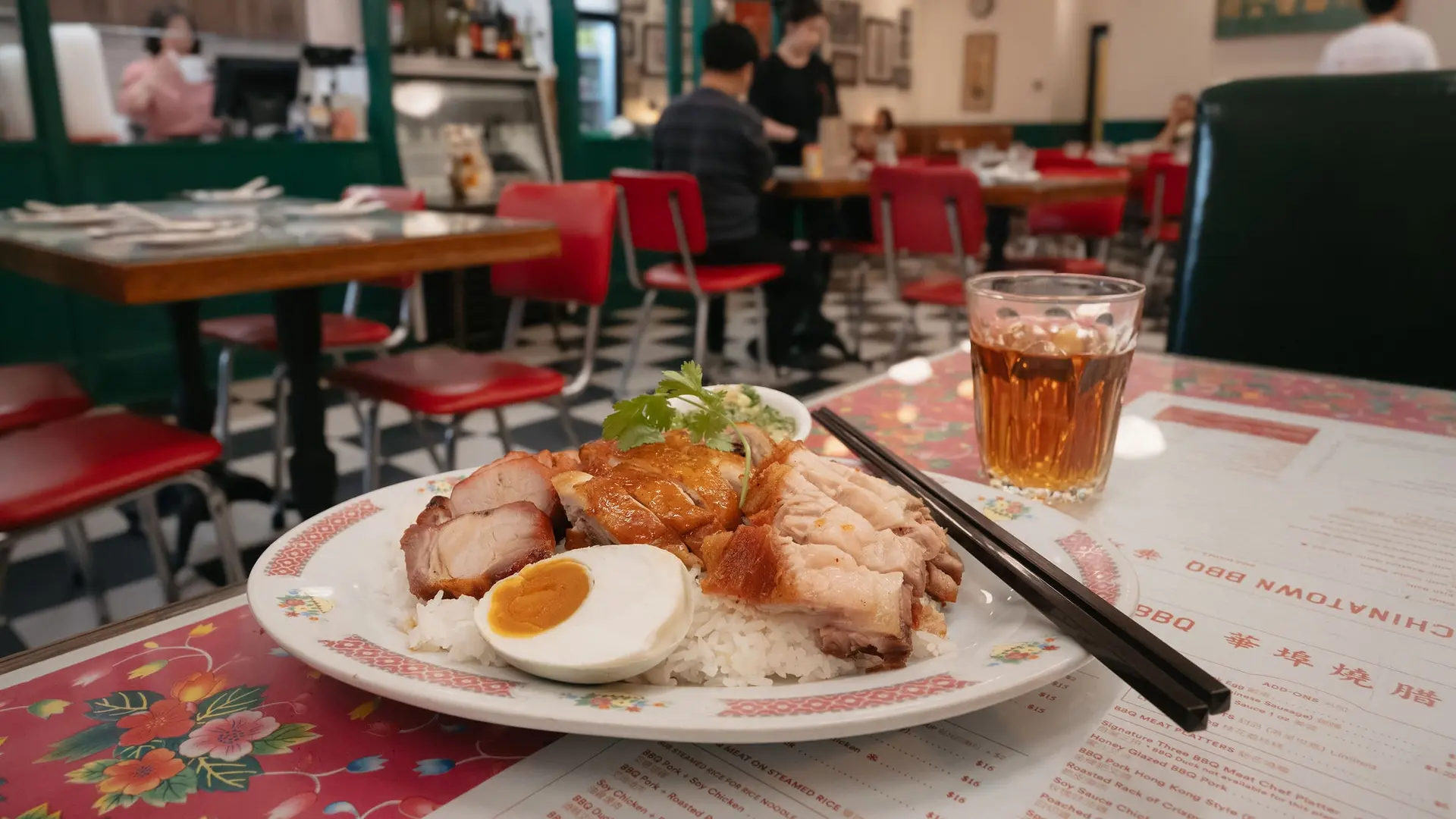 A plate of rice topped with crispy pork and half a boiled egg, served on a table at Chinatown BBQ restaurant.
