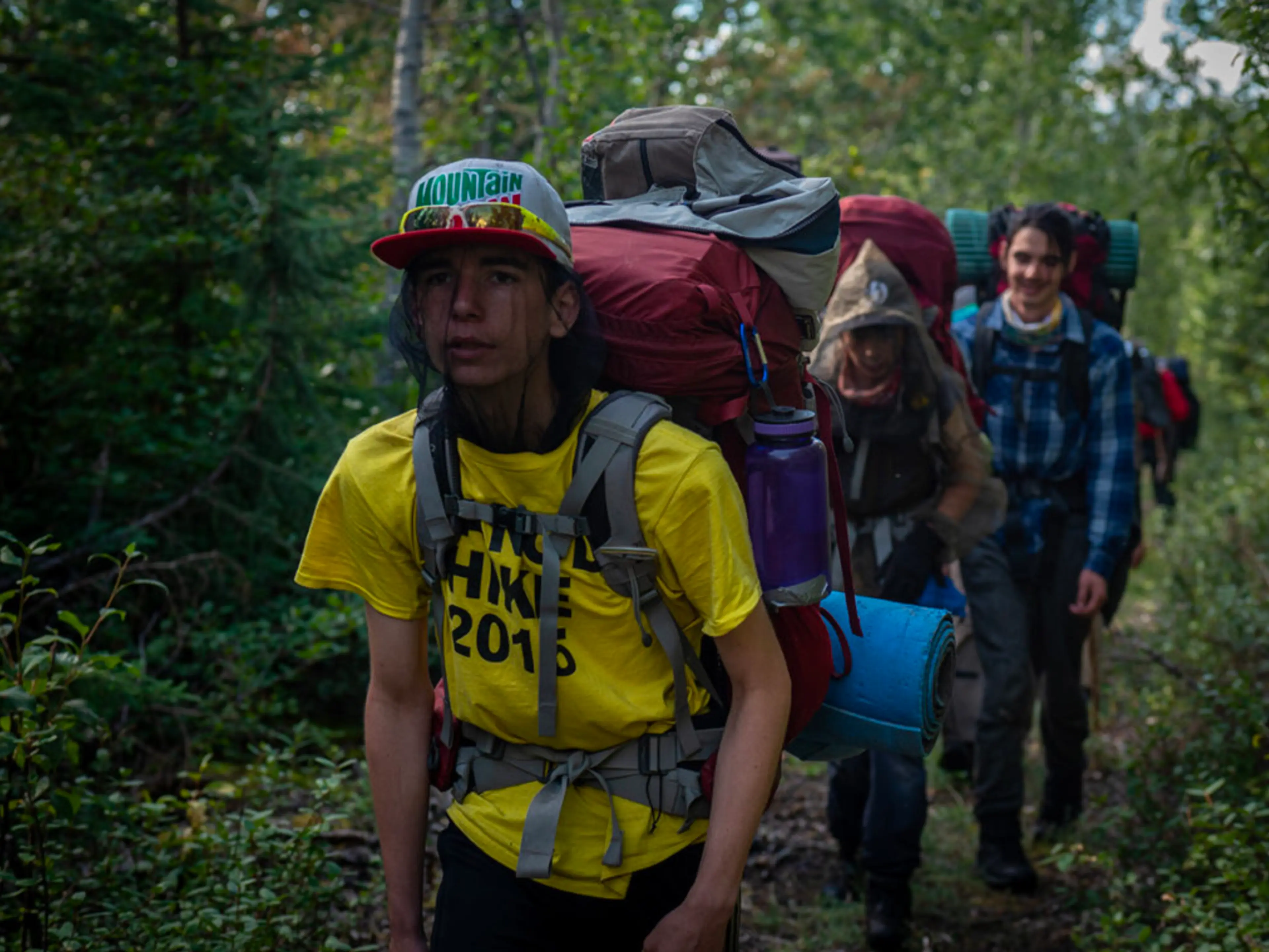 Indigenous youth hike through the forest in a still from the film In the Footsteps of Our Ancestors