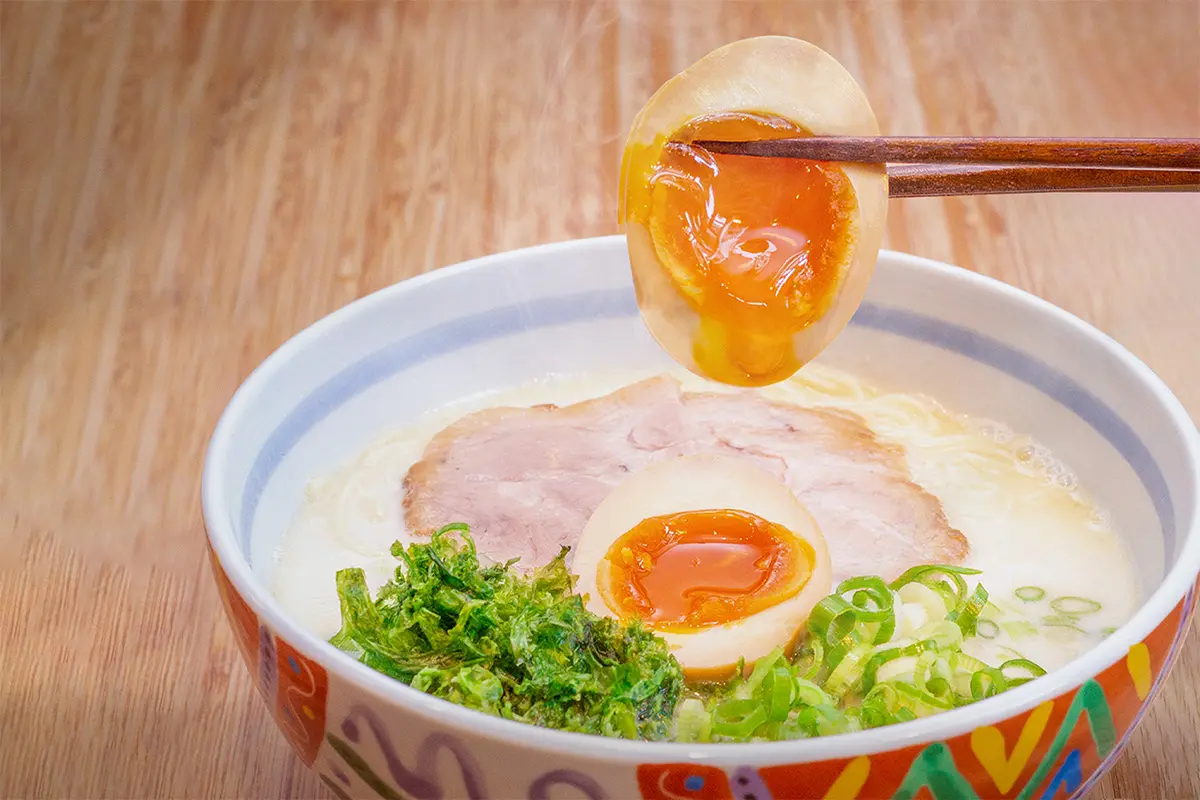 Chopsticks holding up egg in tamago ramen at Maruhachi Ra-men