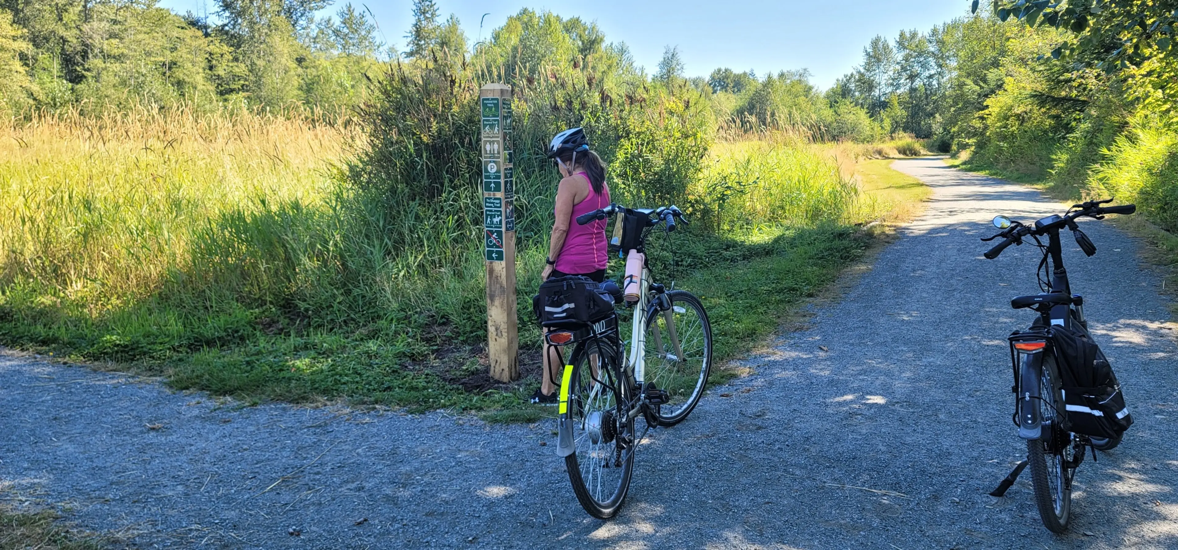 A woman gets off her bike to look at a sign along the Perimeter Trail in Campbell Valley Regional Park