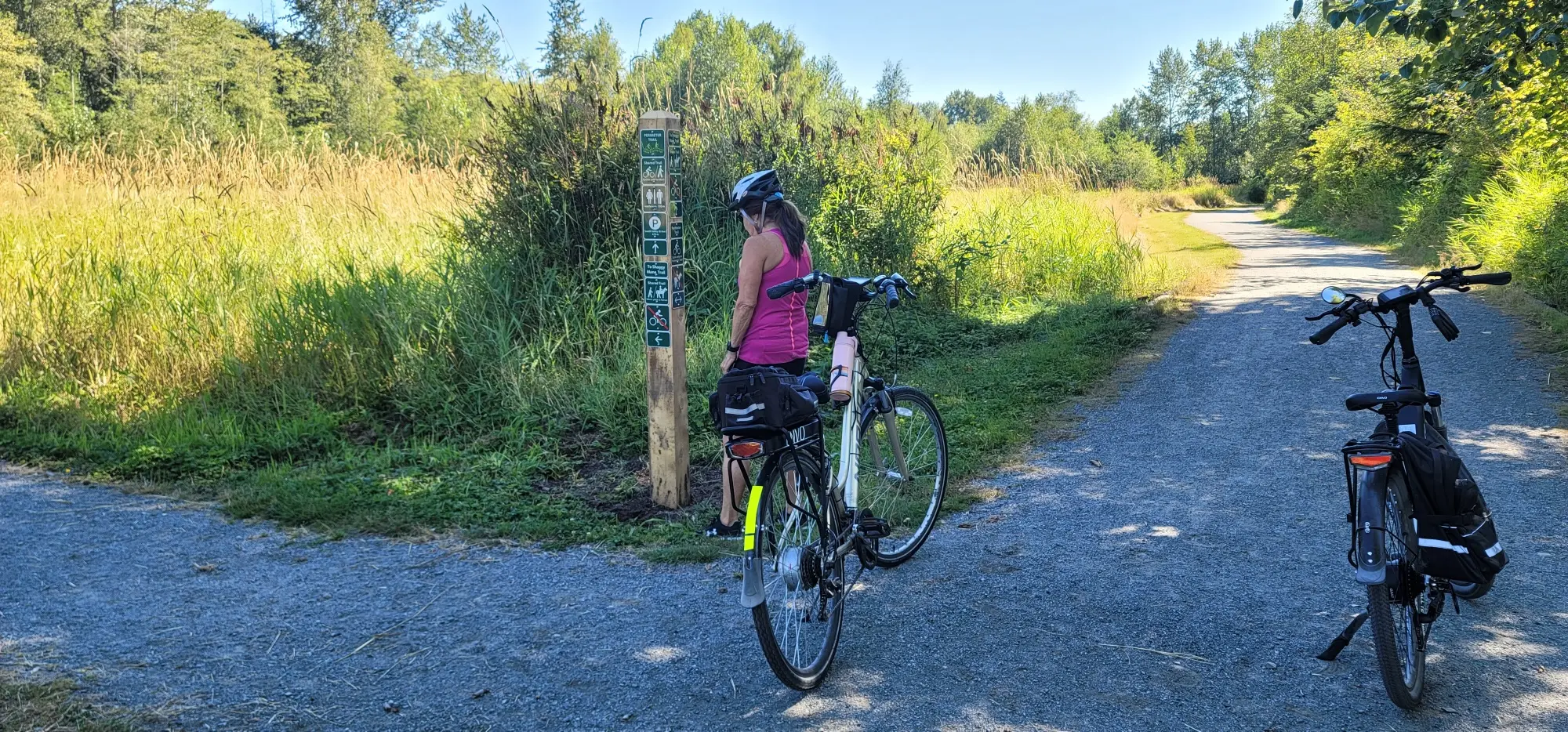 A woman gets off her bike to look at a sign along the Perimeter Trail in Campbell Valley Regional Park