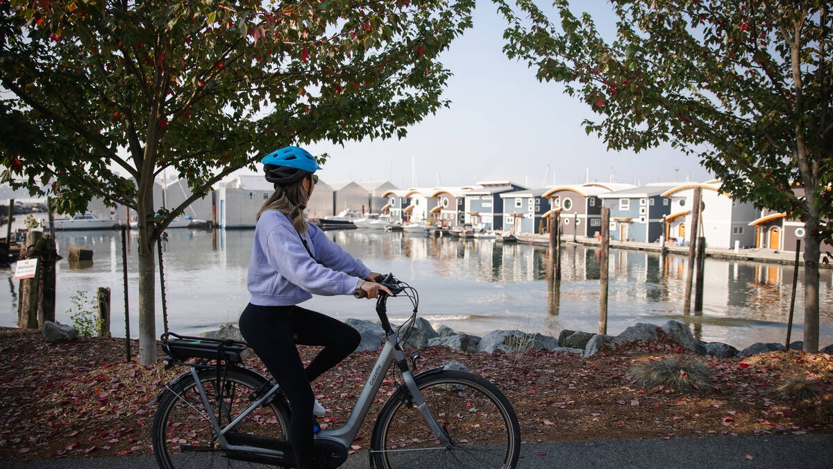 A woman wearing a bike helmet bikes along the Spirit Trail in North Vancouver