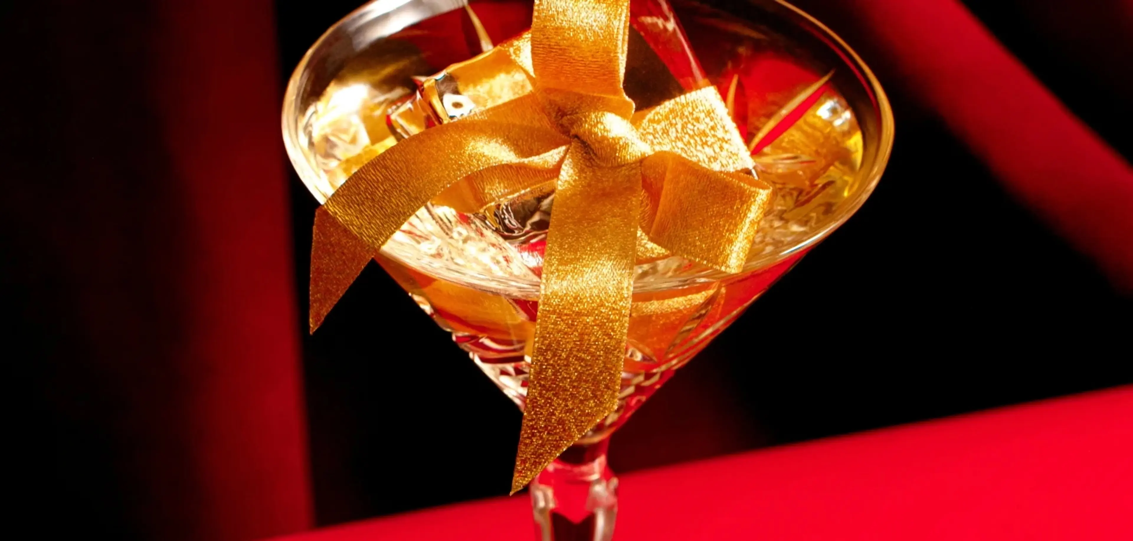 A close-up of a holiday-themed drink at Kringle's at the Hotel Vancouver. The cocktail has an ice cube that is wrapped like a holiday gift. 