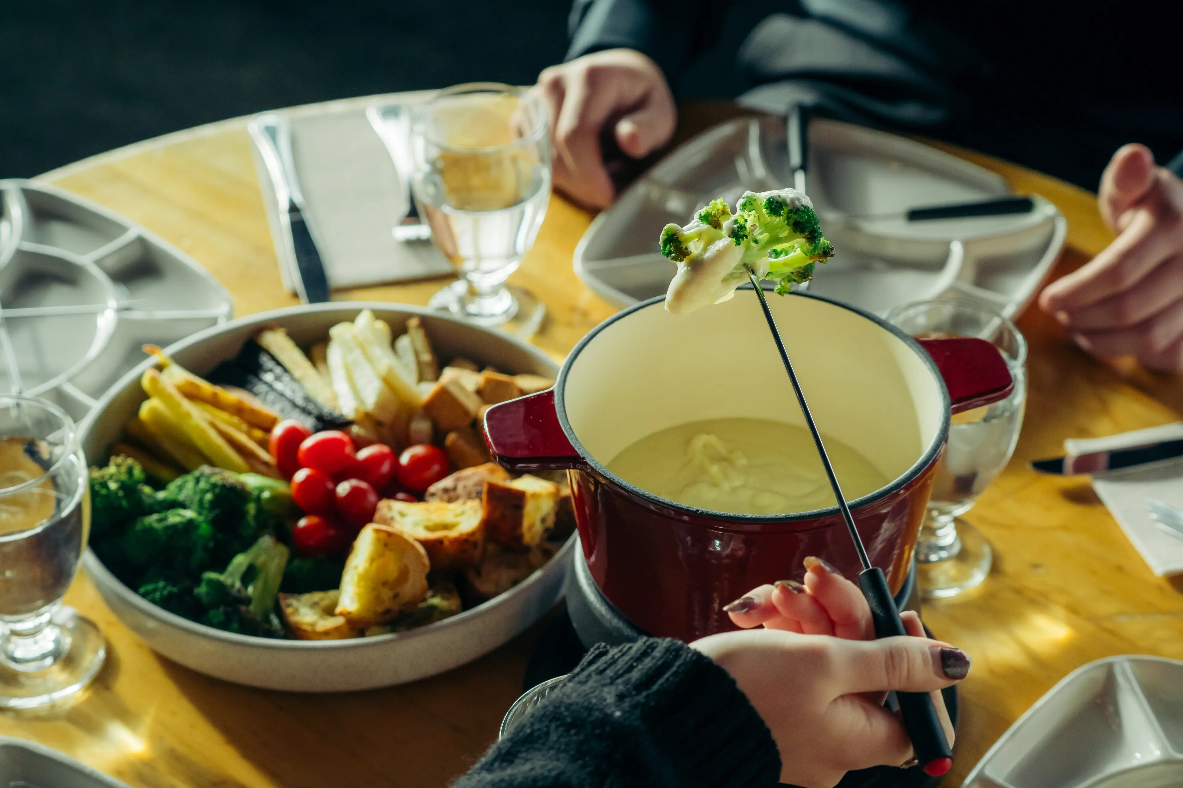 A cheese fondue pot and a spread of veggies and bread for dipping on a table at Altitudes Bistro at Grouse Mountain