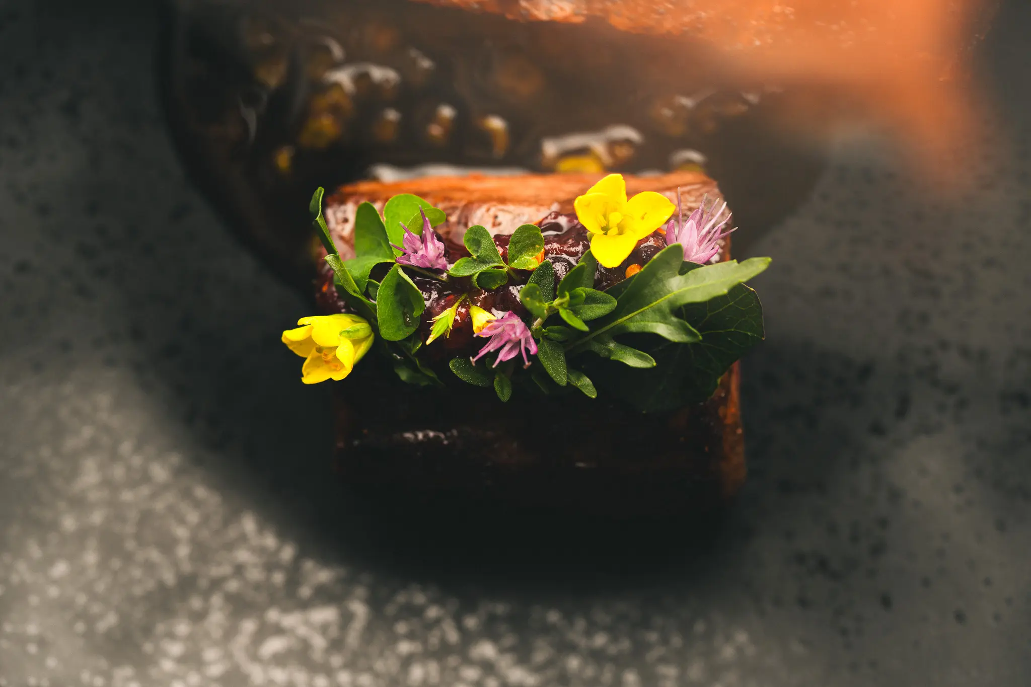 A beautifully plated dish at Burdock & Co. in Vancouver, topped with delicate edible flowers.