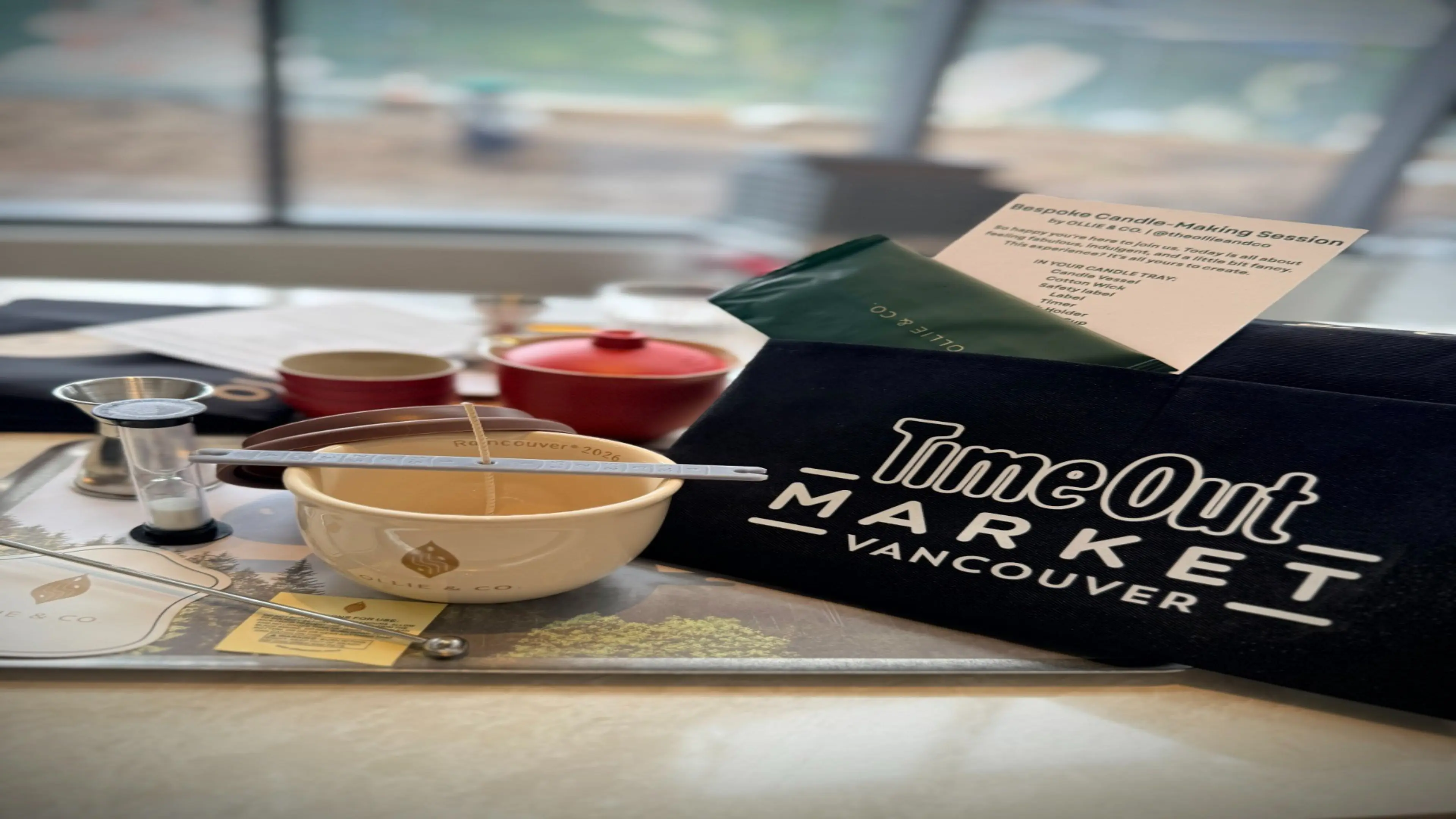 Candle-making kit with bowl, wick, thermometer, and TimeOut Market Vancouver bag on a table.