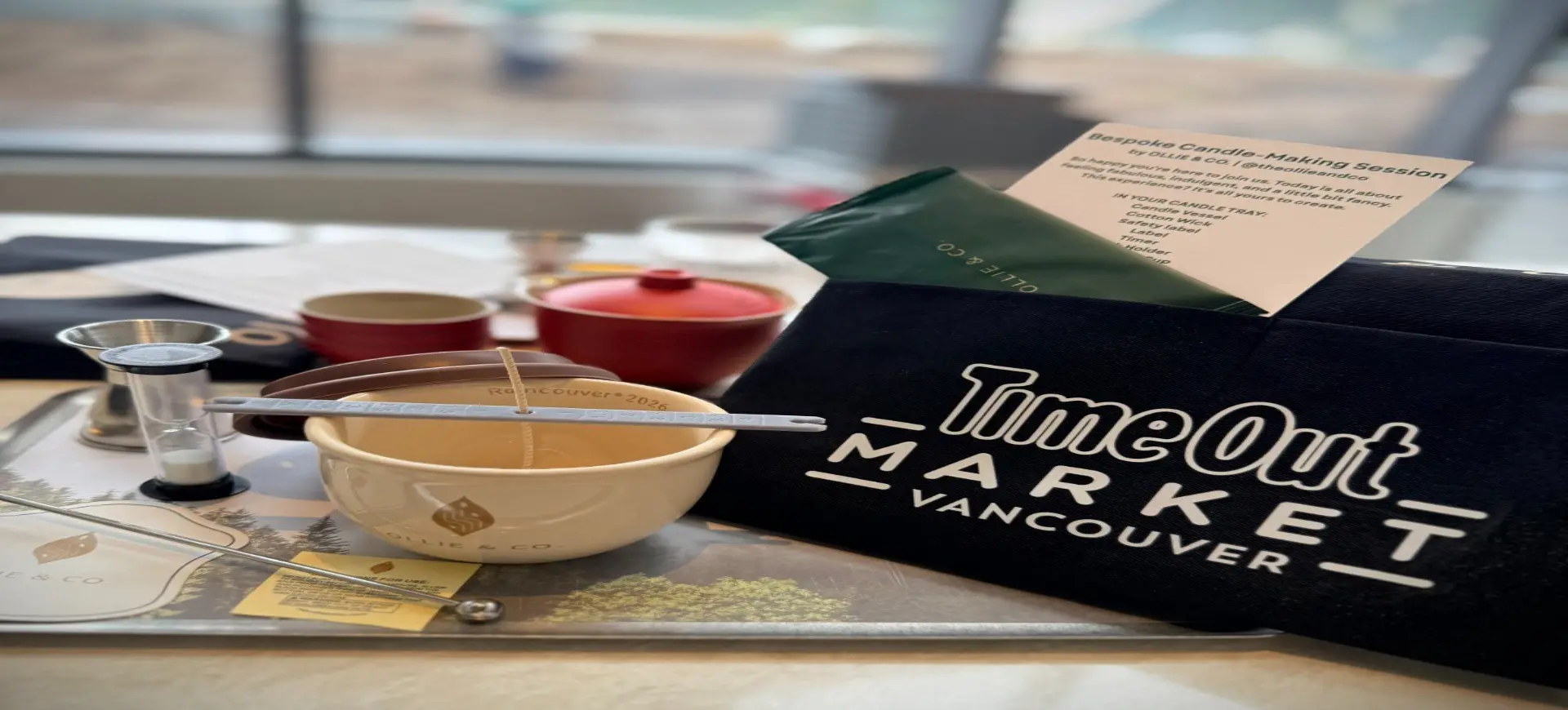 Candle-making kit with bowl, wick, thermometer, and TimeOut Market Vancouver bag on a table.