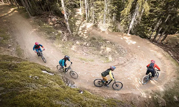 Mountain bikers descend a curve in the mountain bike park in Whistler, BC