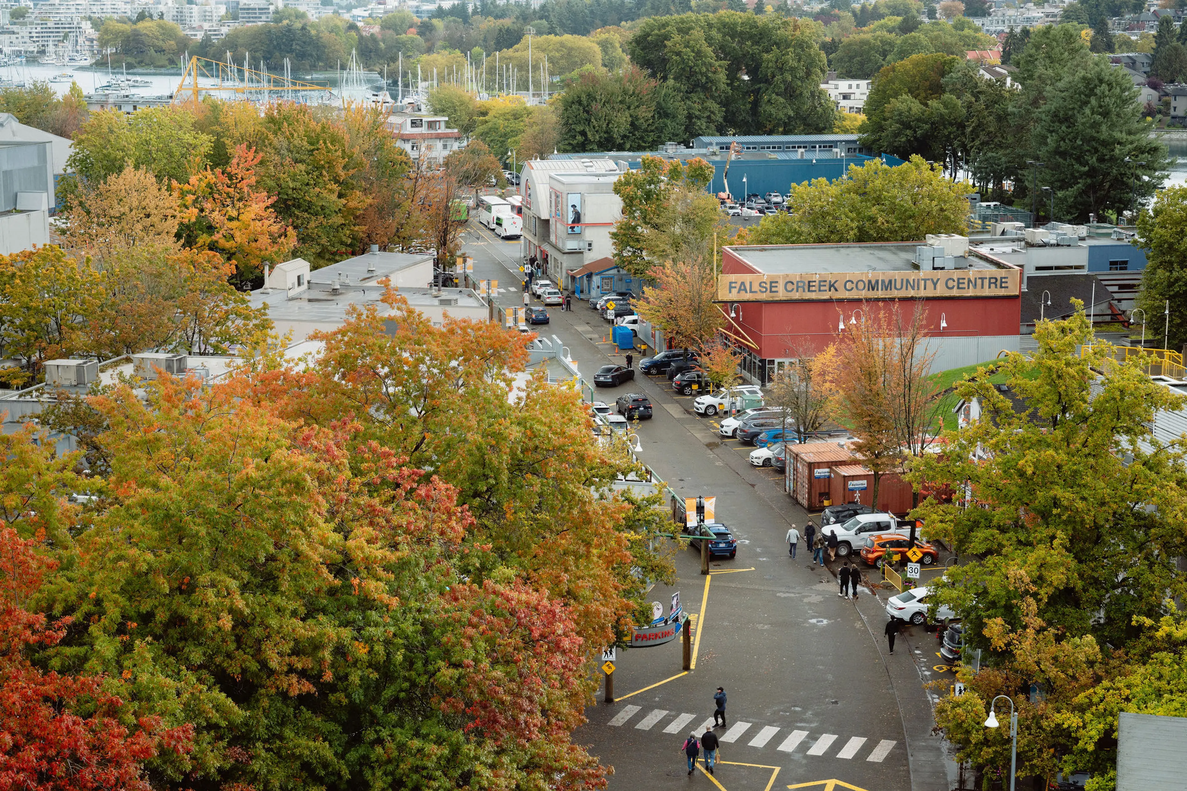 Street view of False Creek Community Centre surrounded by trees with autumn foliage and parked cars.