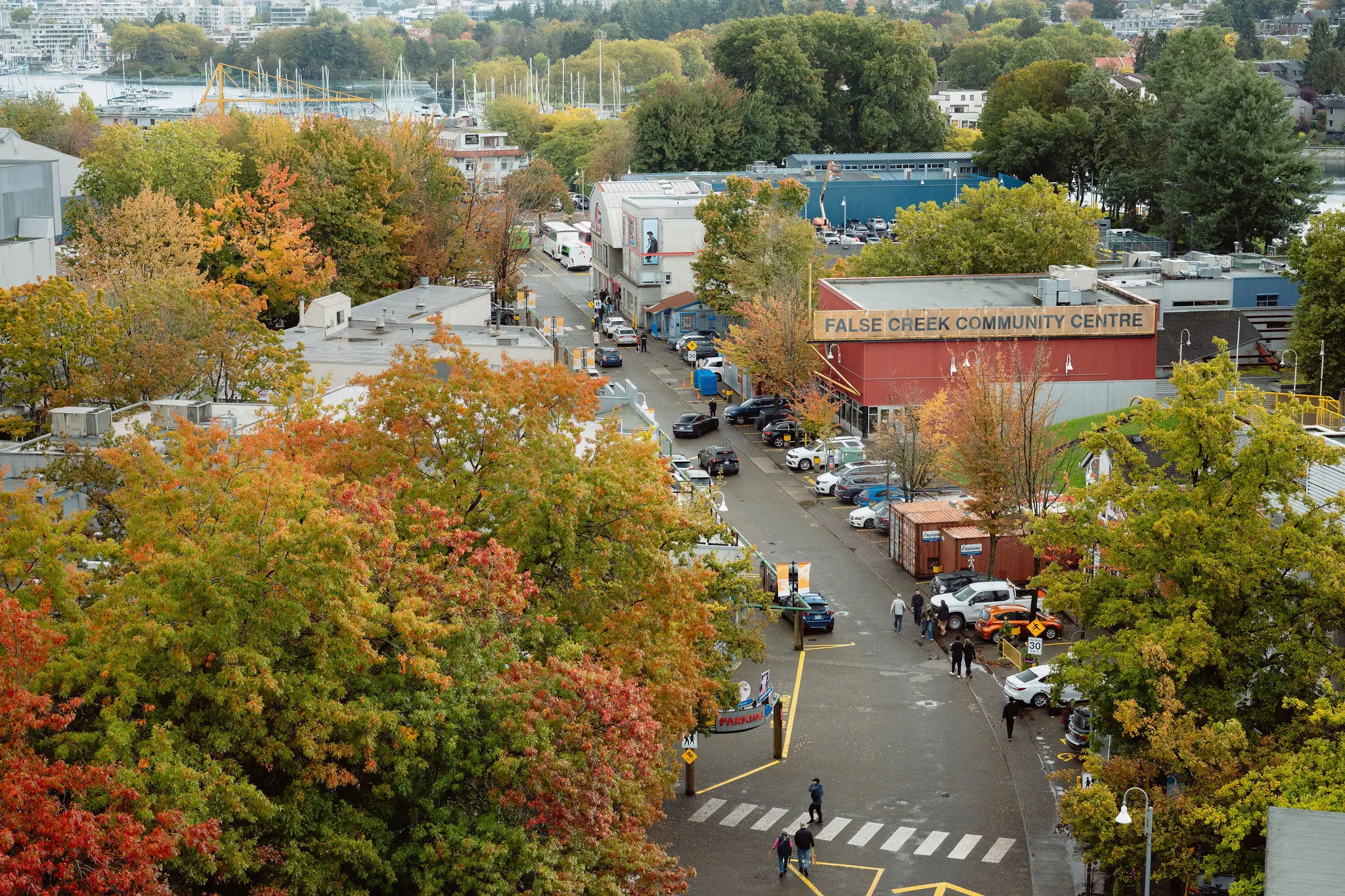 Street view of False Creek Community Centre surrounded by trees with autumn foliage and parked cars.