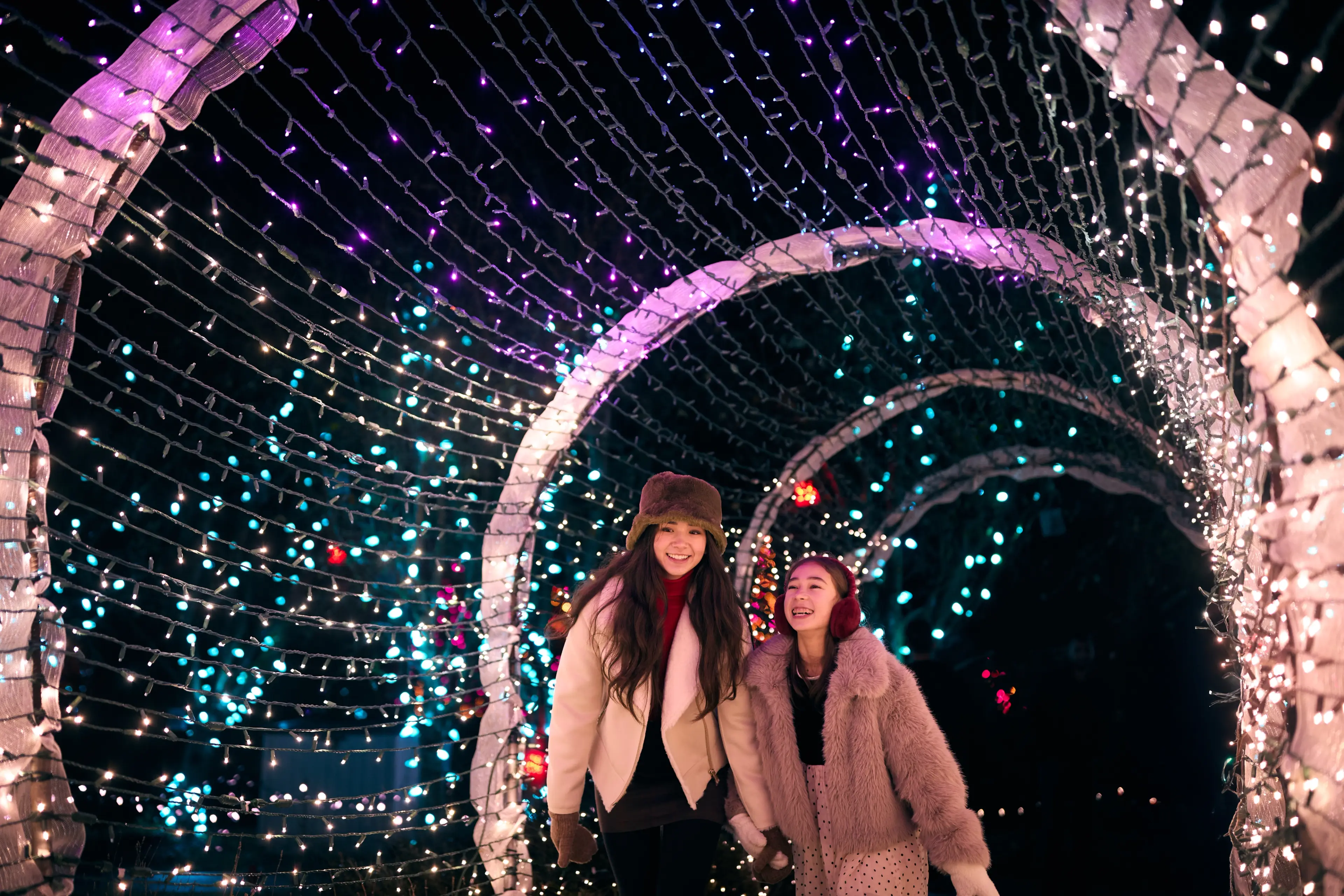 Two kids walking through a tunnel of festive lights at the VanDusen Festival of Lights, Vancouver.