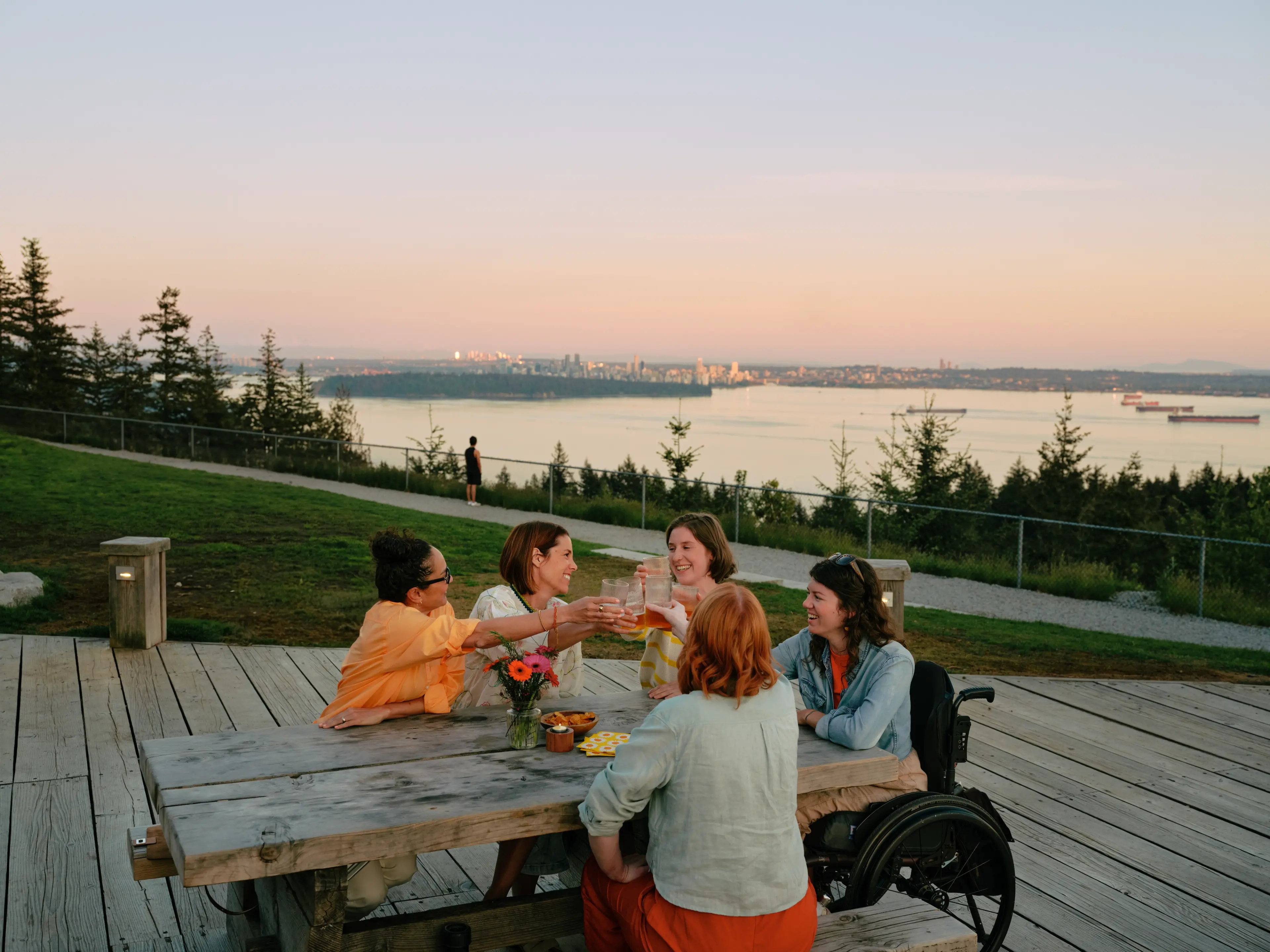 People enjoy drinks at the Cypress Pop-up at sunset with the city in the background. 