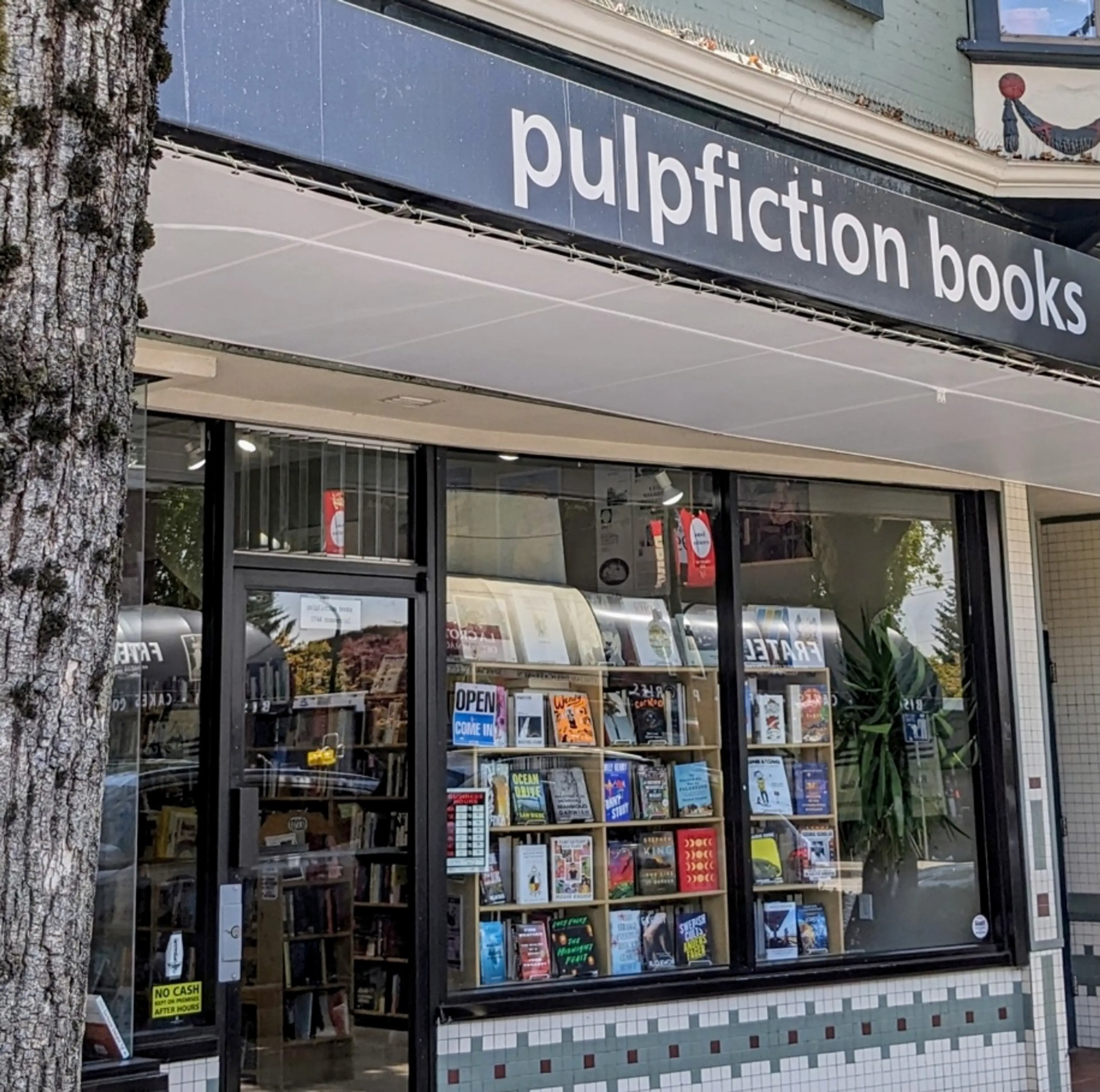 The exterior of Pulp Fiction Books in Vanocuver. There is an awning over the window and lots of books on display.